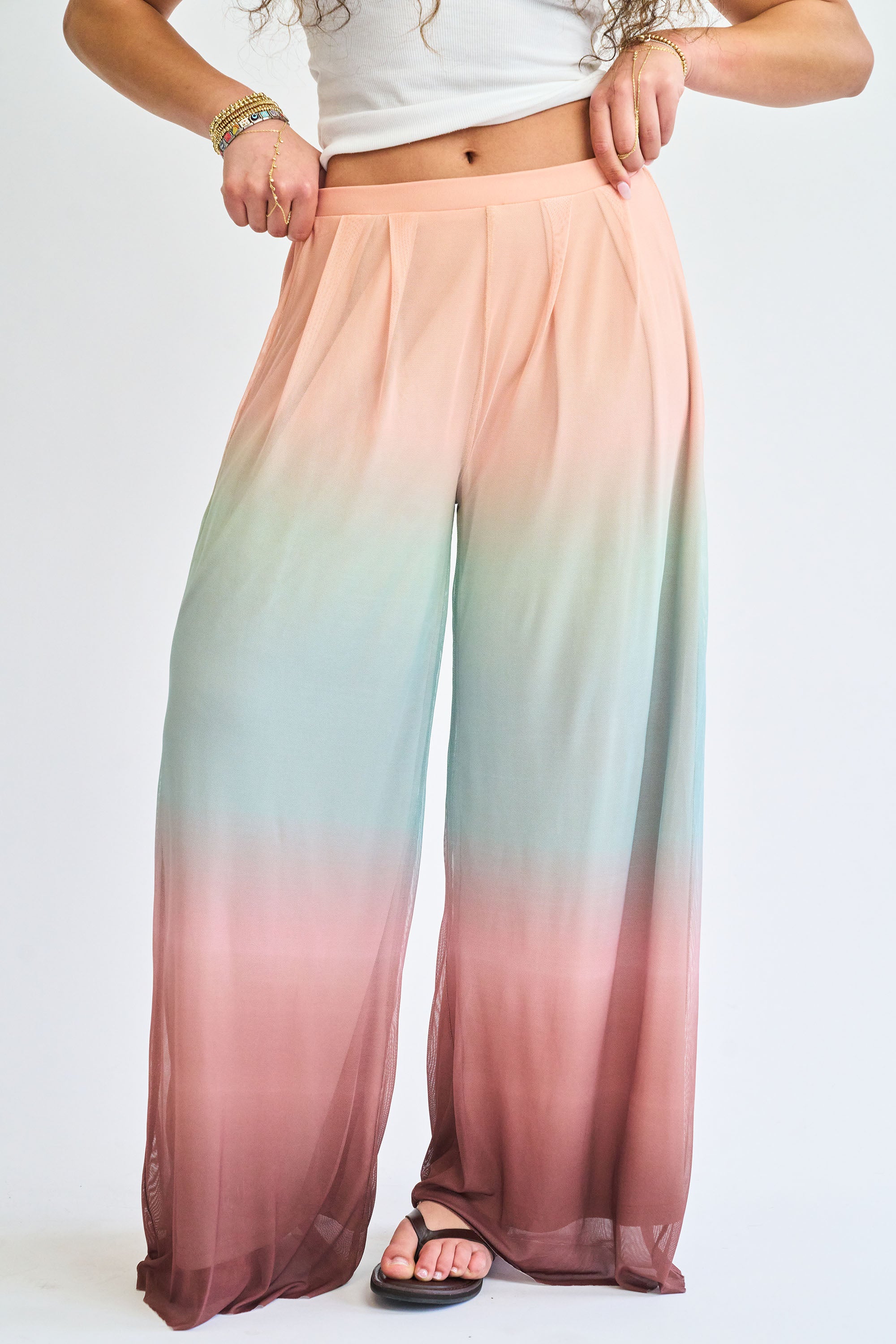 Ombre pants with a gradient from pink to green on a plain background