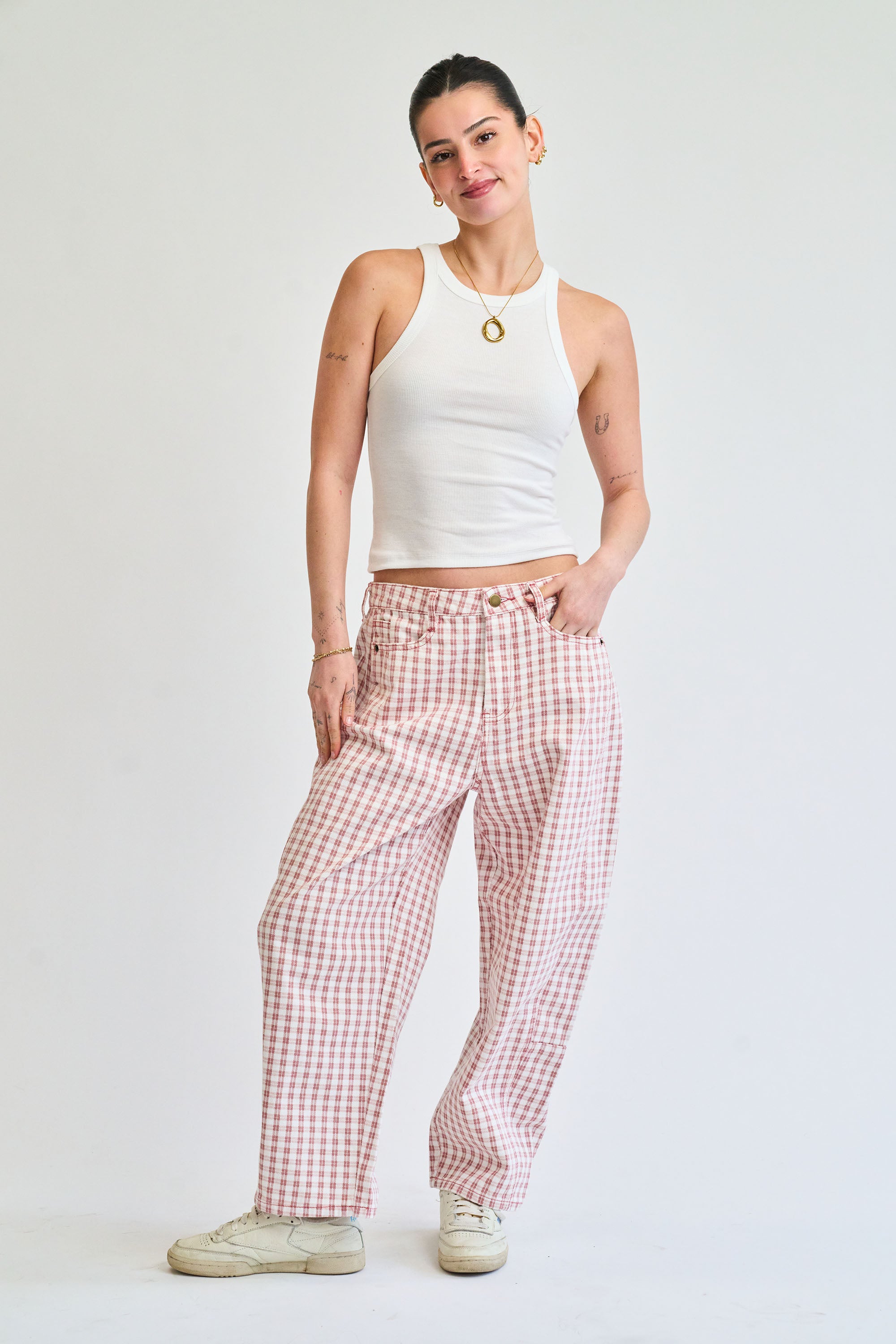 Woman wearing a white tank top and red checkered pants on a white background