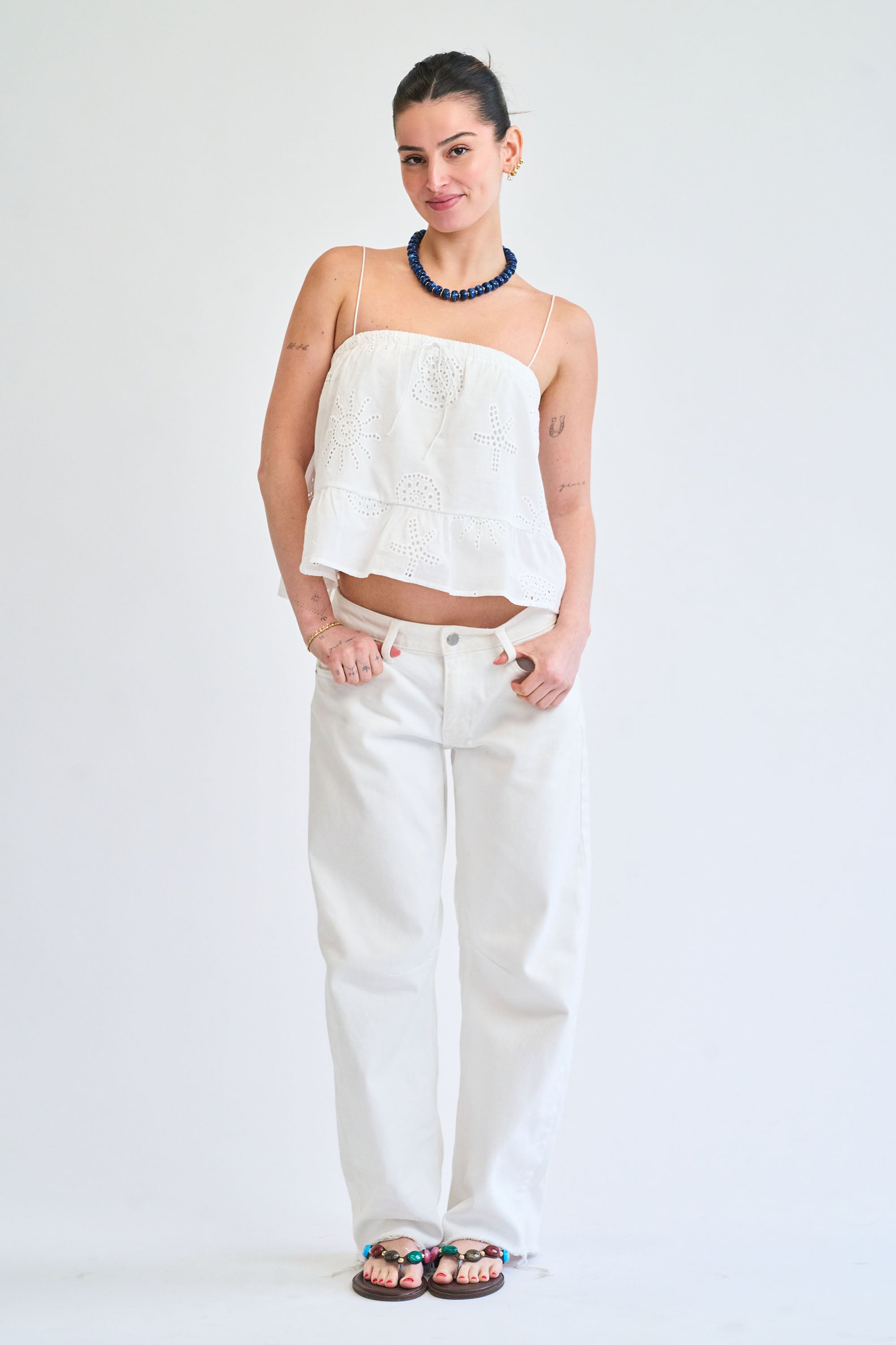Woman wearing a white top and pants on a plain background