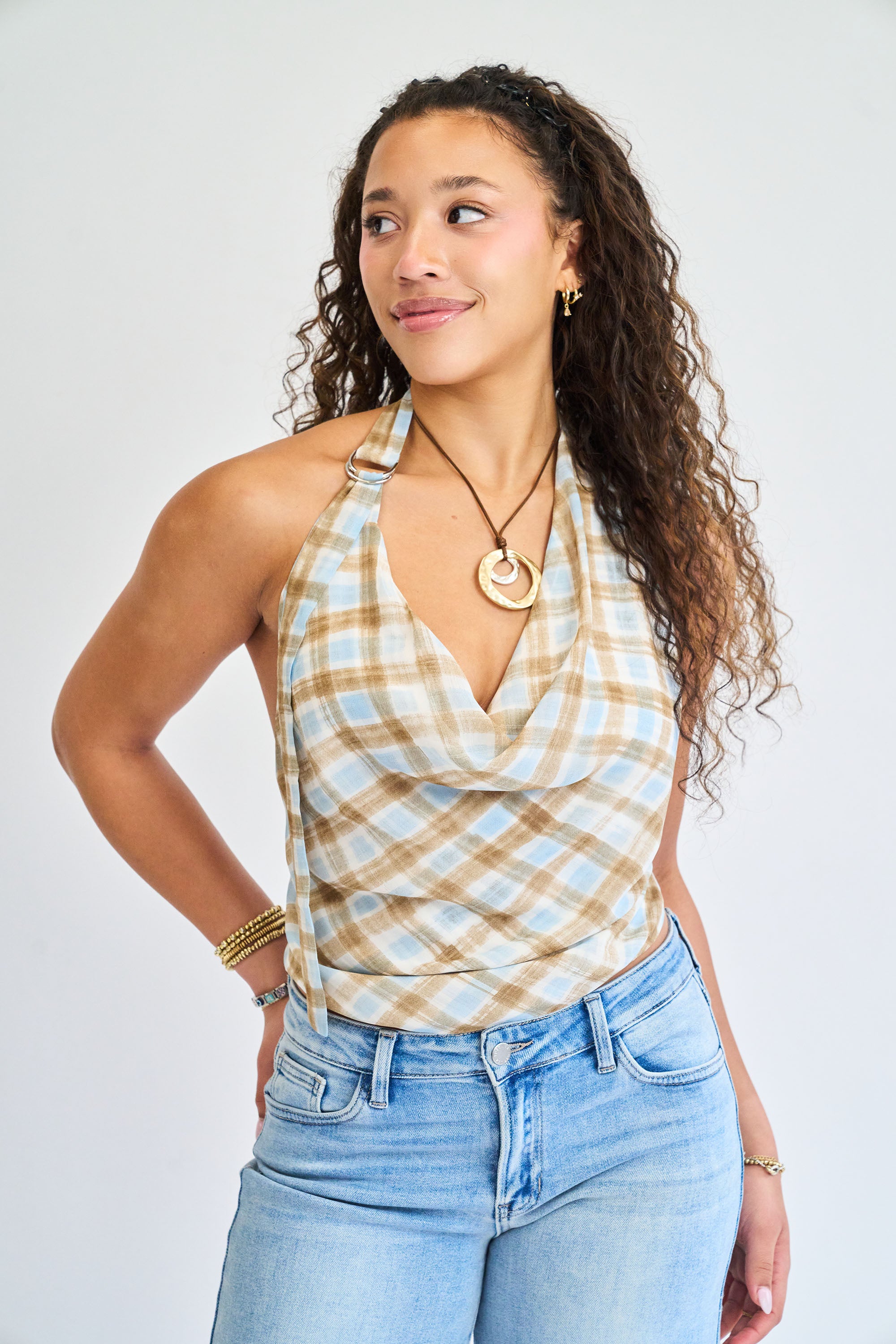 Woman wearing a plaid halter top and jeans against a plain background