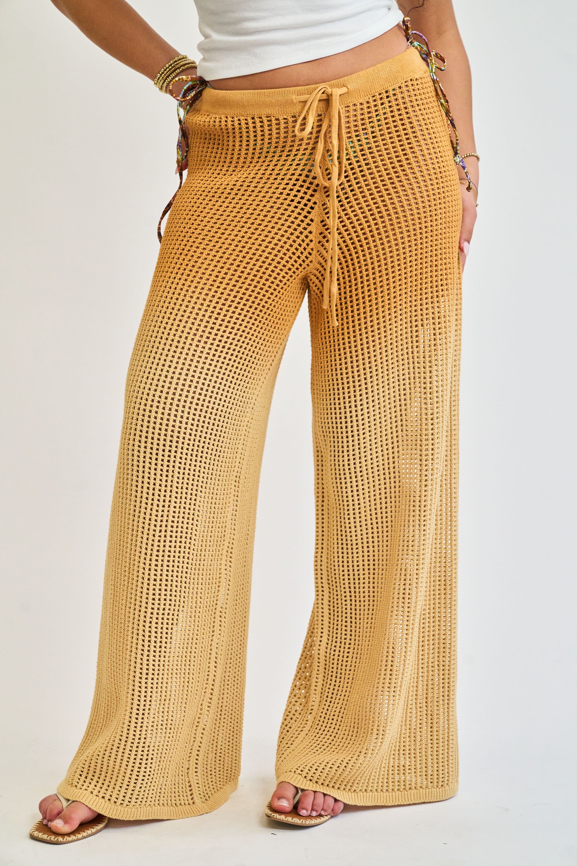 Mustard yellow knitted pants worn by a person on a white background