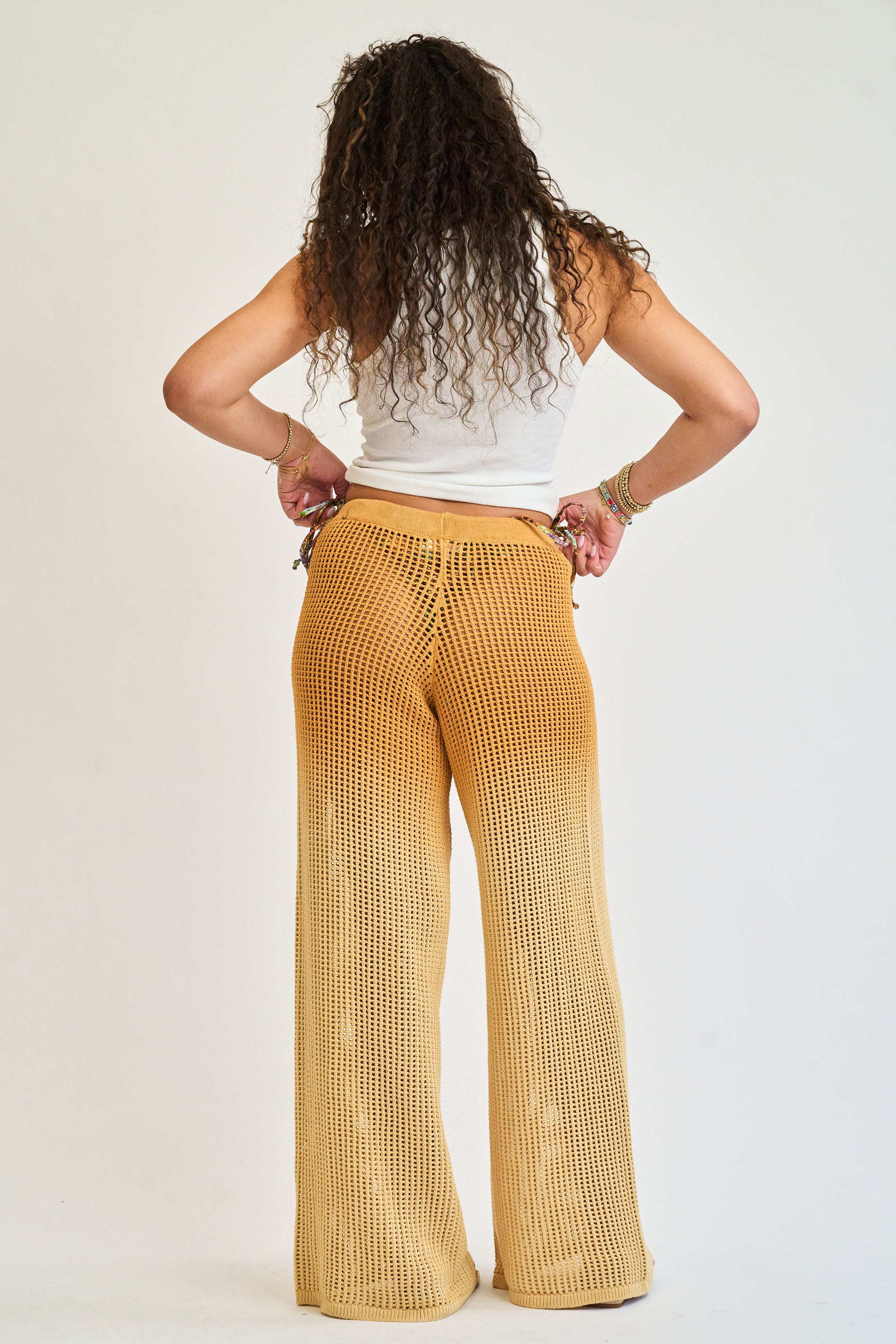 Person wearing mustard yellow pants and a white top on a plain background