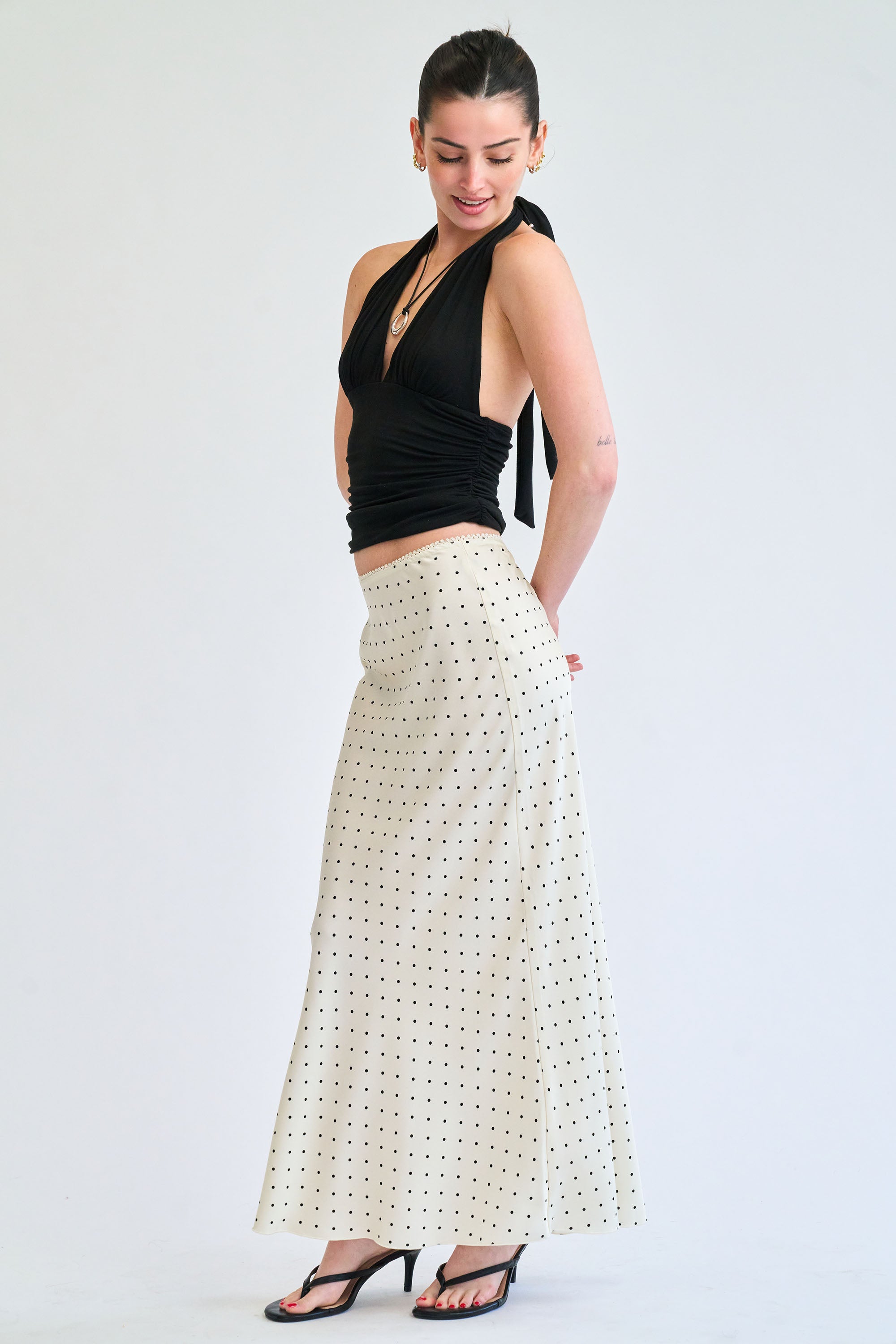 Woman wearing a black top and white patterned skirt on a white background