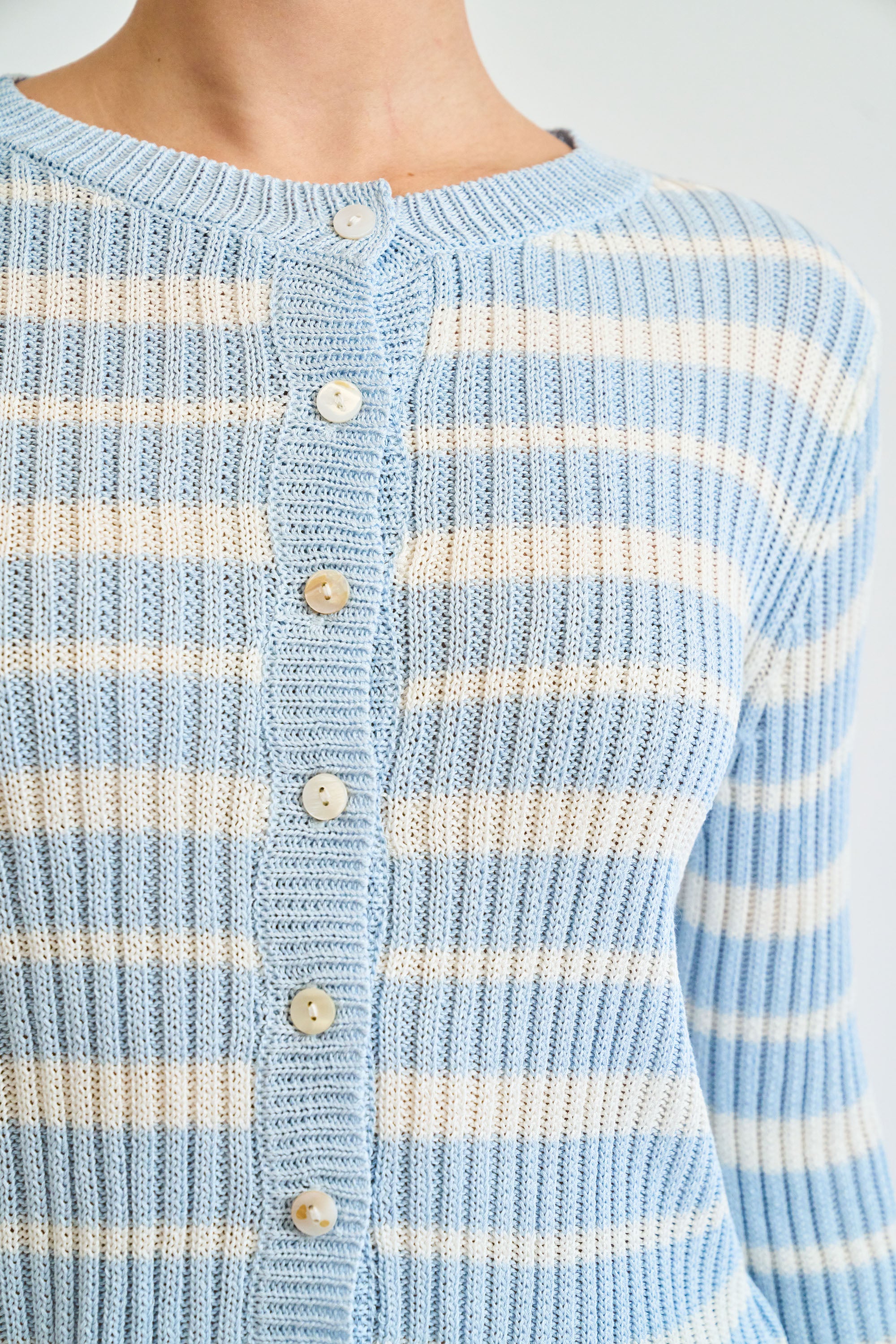 Close-up of a light blue and white striped cardigan with buttons.