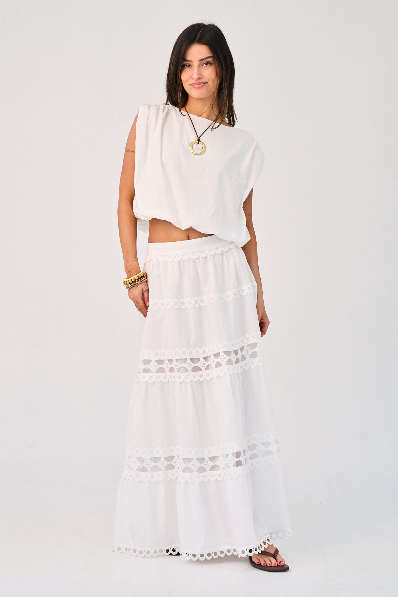 Woman wearing a white outfit with lace details on a plain background