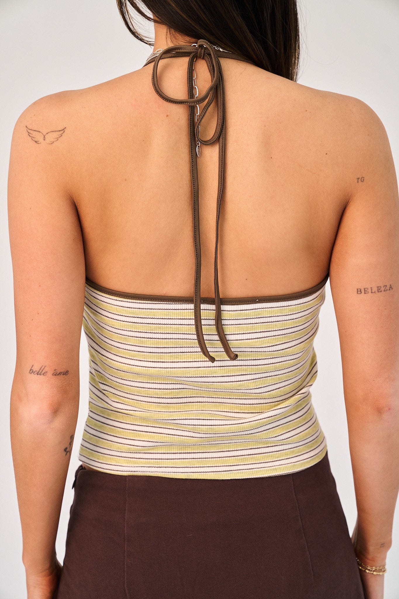 Woman wearing a striped halter top with a plain background
