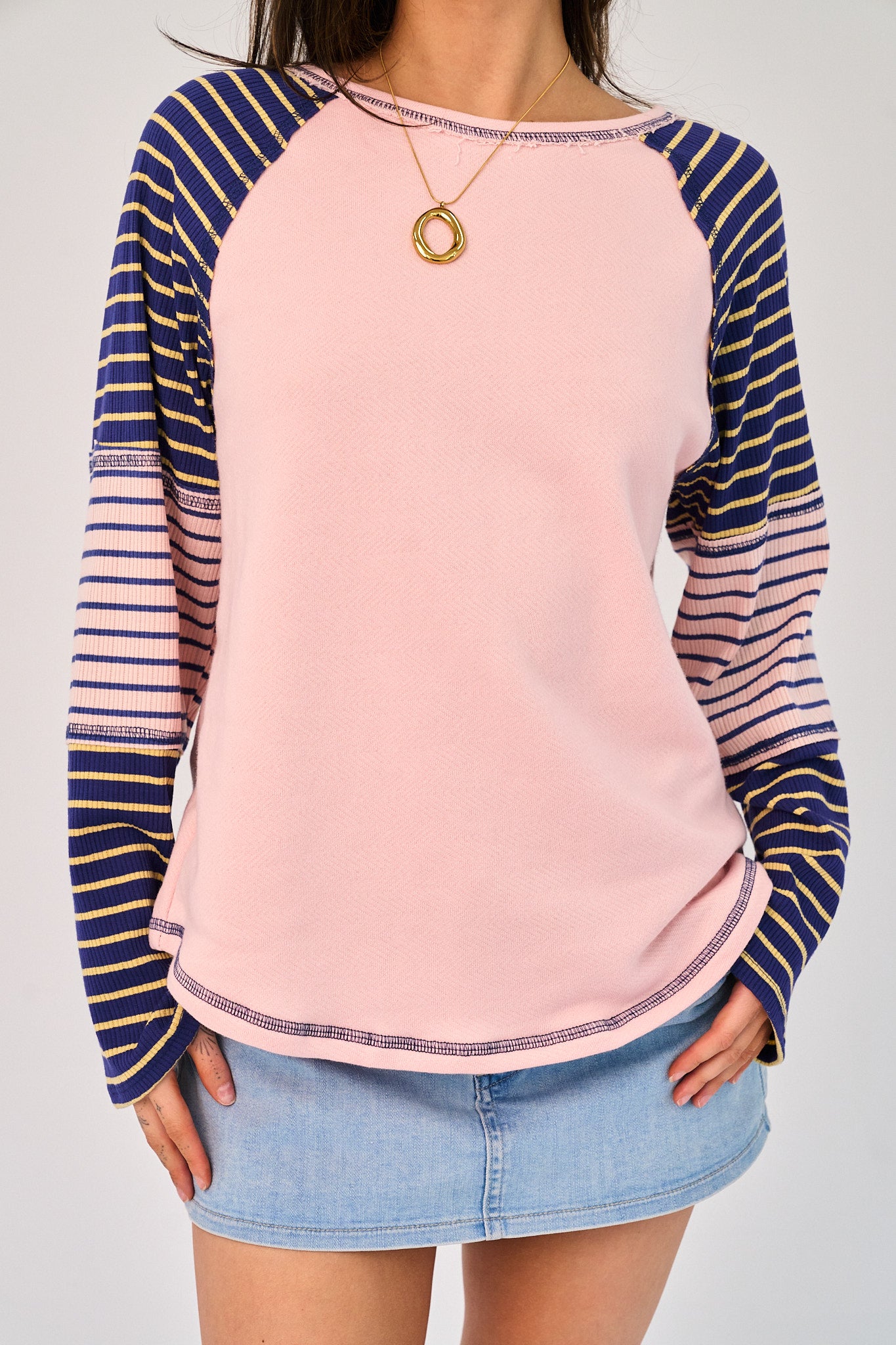 Person wearing a pink and blue striped long-sleeve top with a plain background