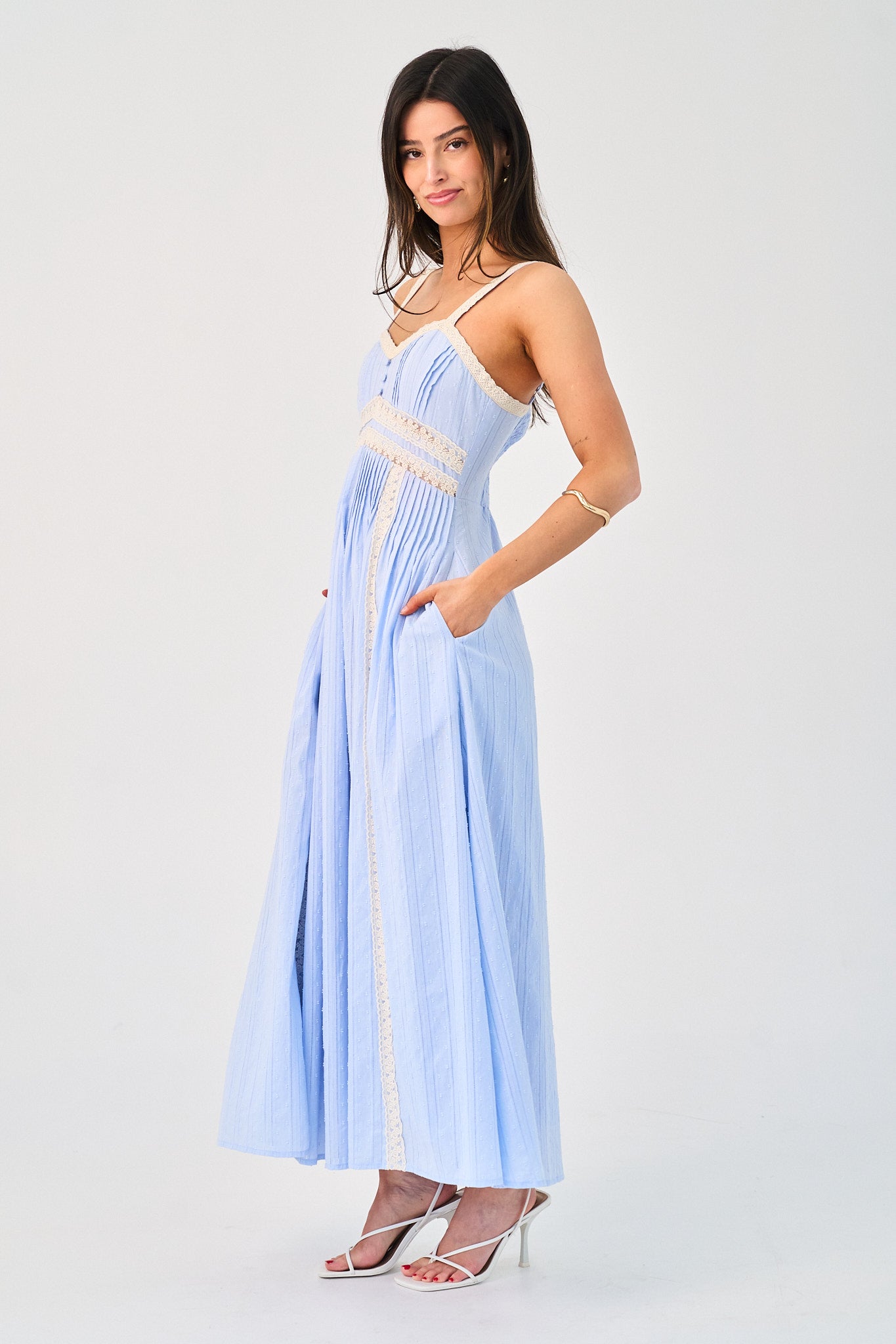 Woman wearing a light blue dress with white lace details on a white background