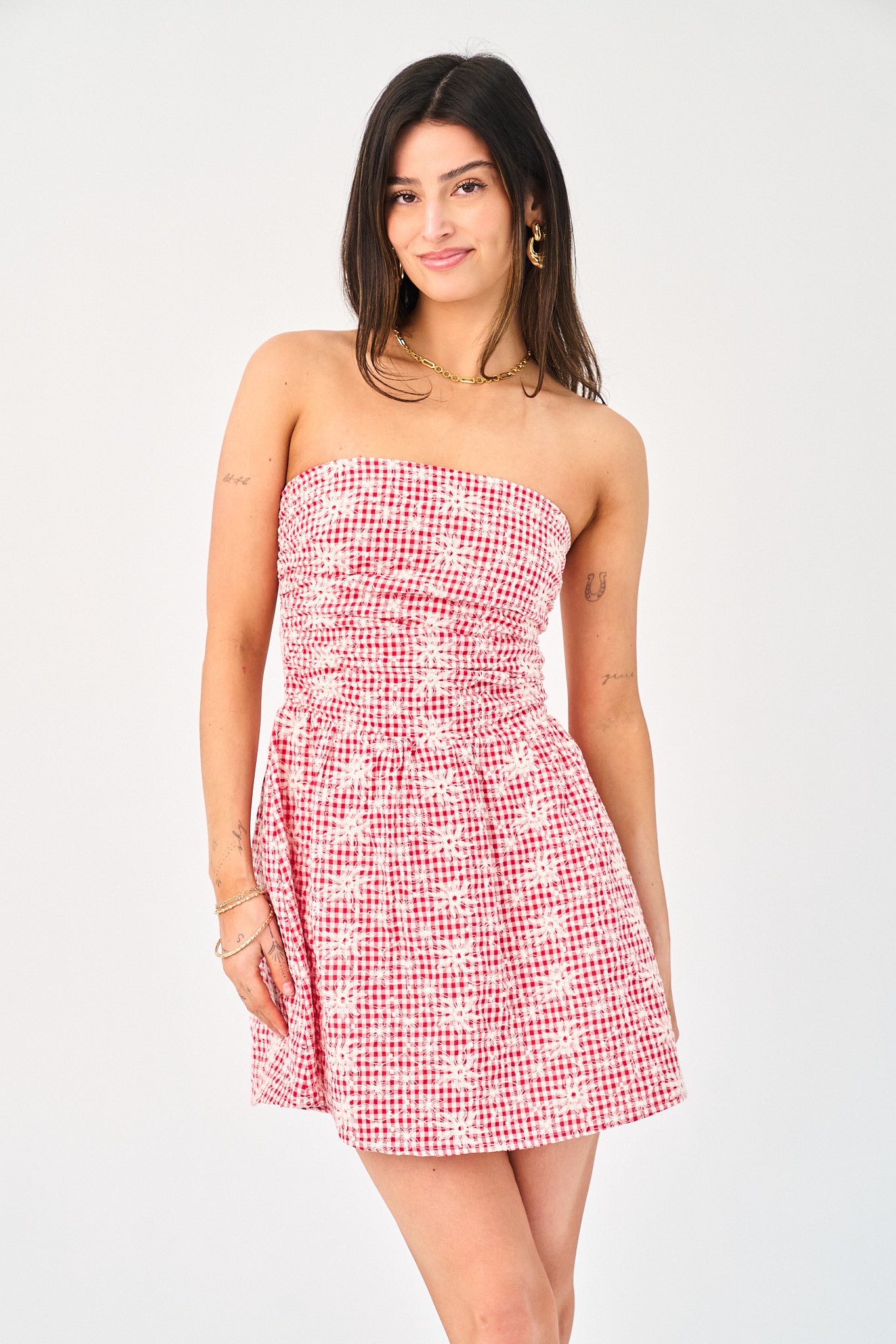 Woman wearing a strapless red and white checkered dress on a white background