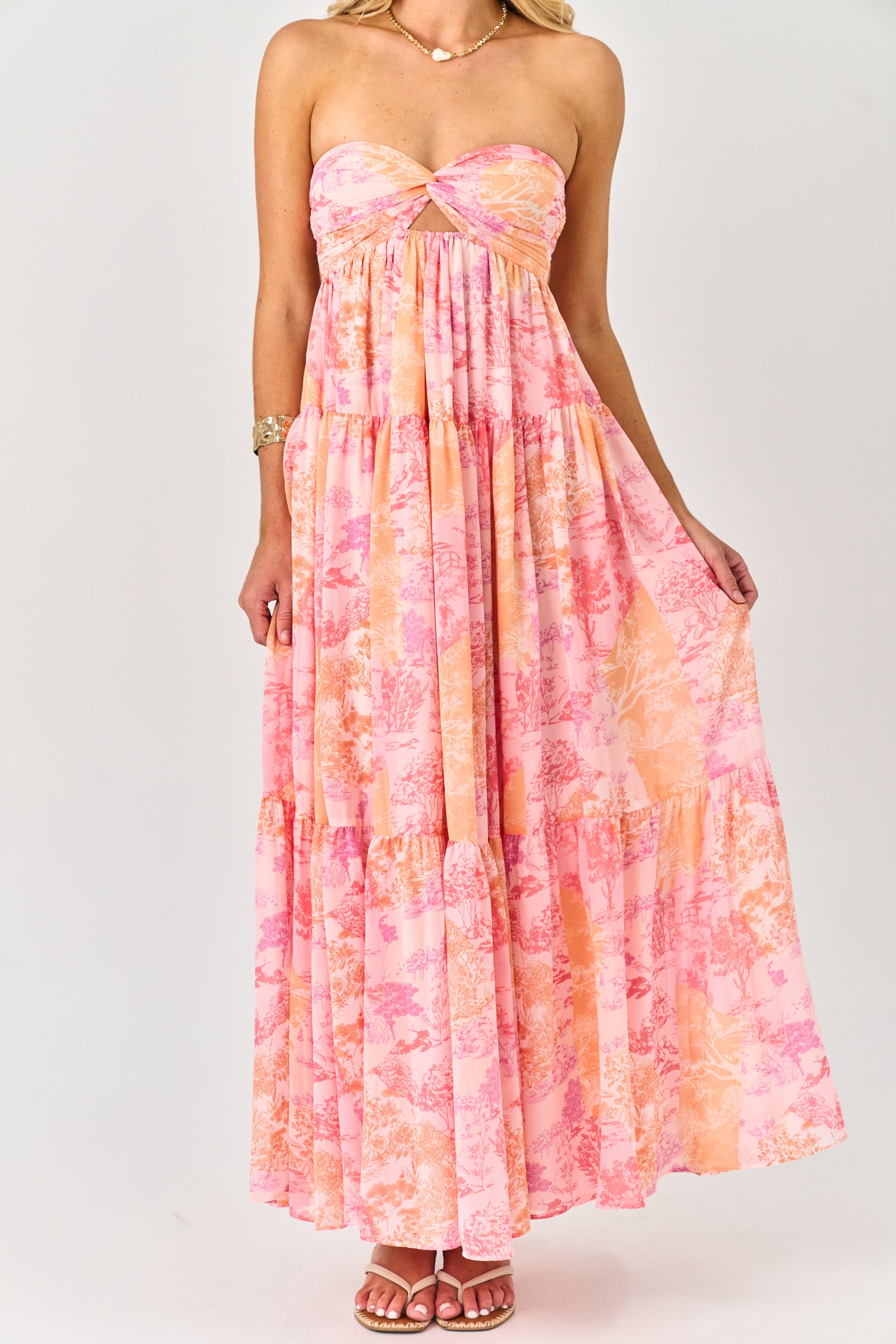 Woman wearing a strapless, tie-dye dress with pink and orange colors on a white background