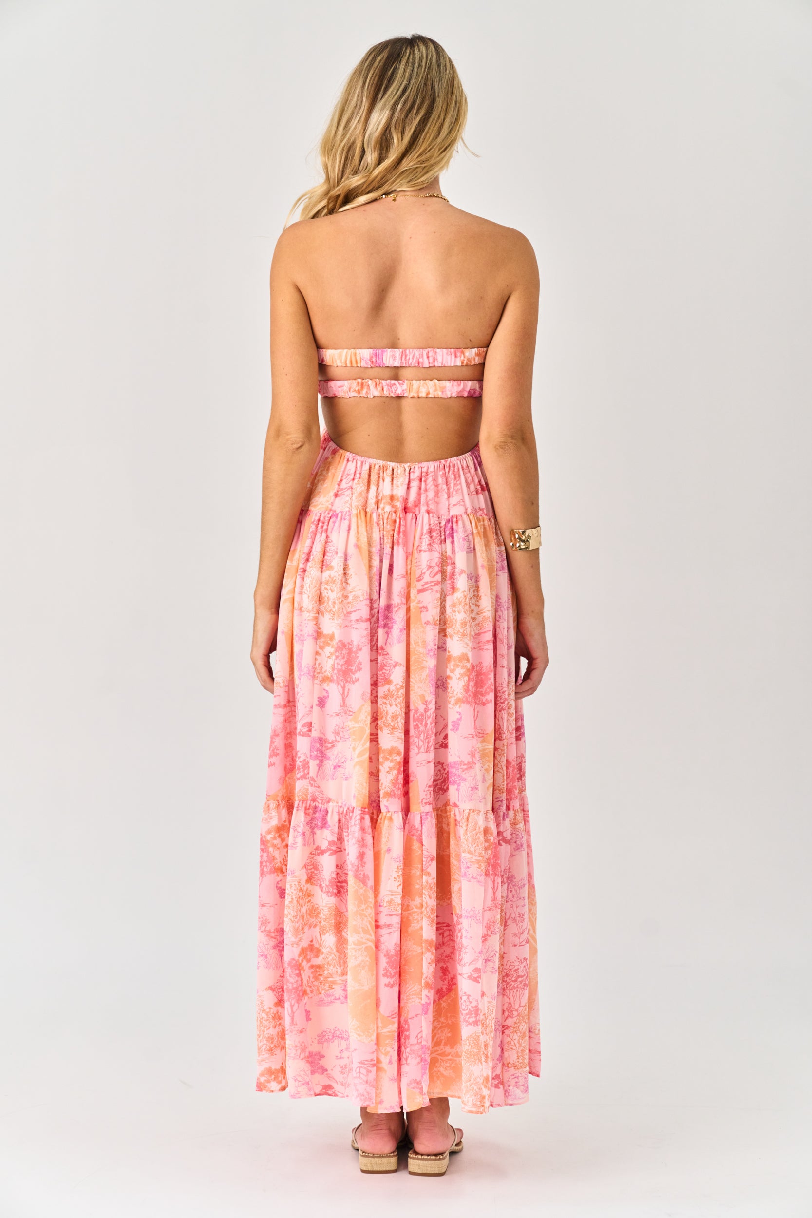 Woman wearing a pink and orange tie-dye dress with a strapless top on a white background