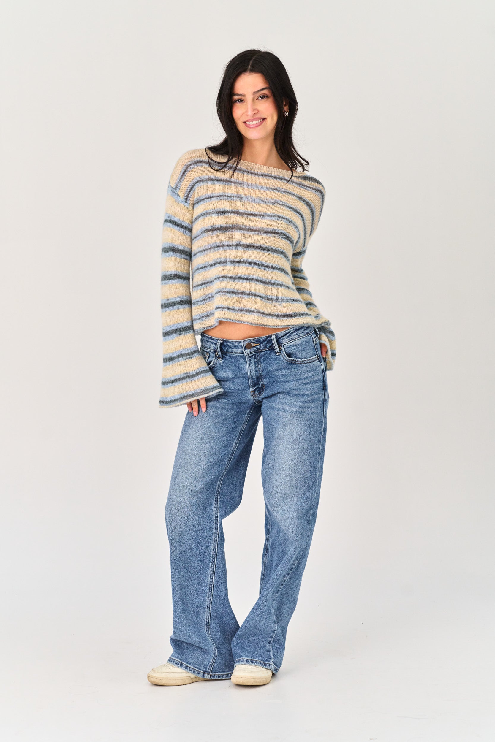 Woman wearing a striped sweater and blue jeans on a white background