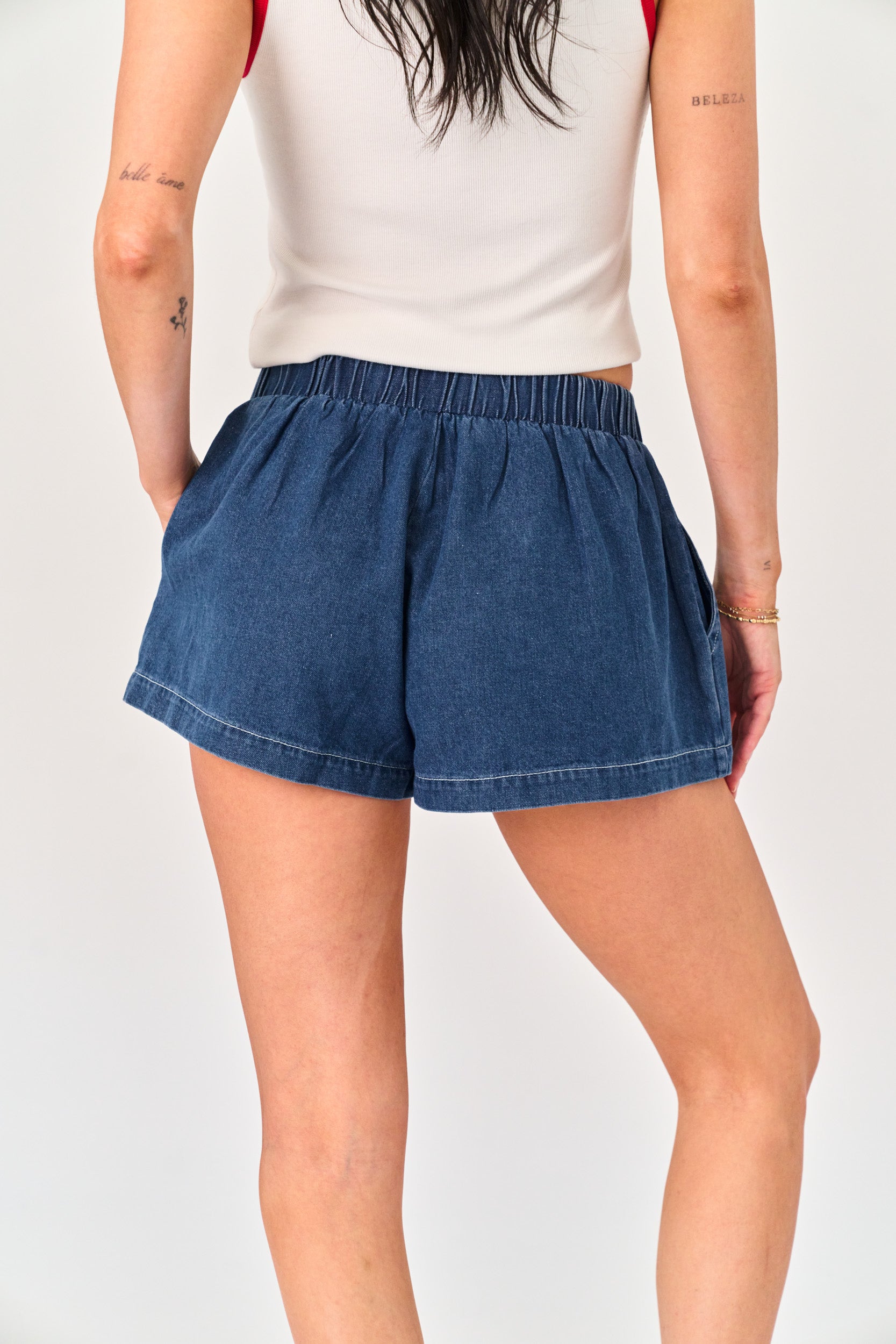 Person wearing blue denim shorts on a plain background