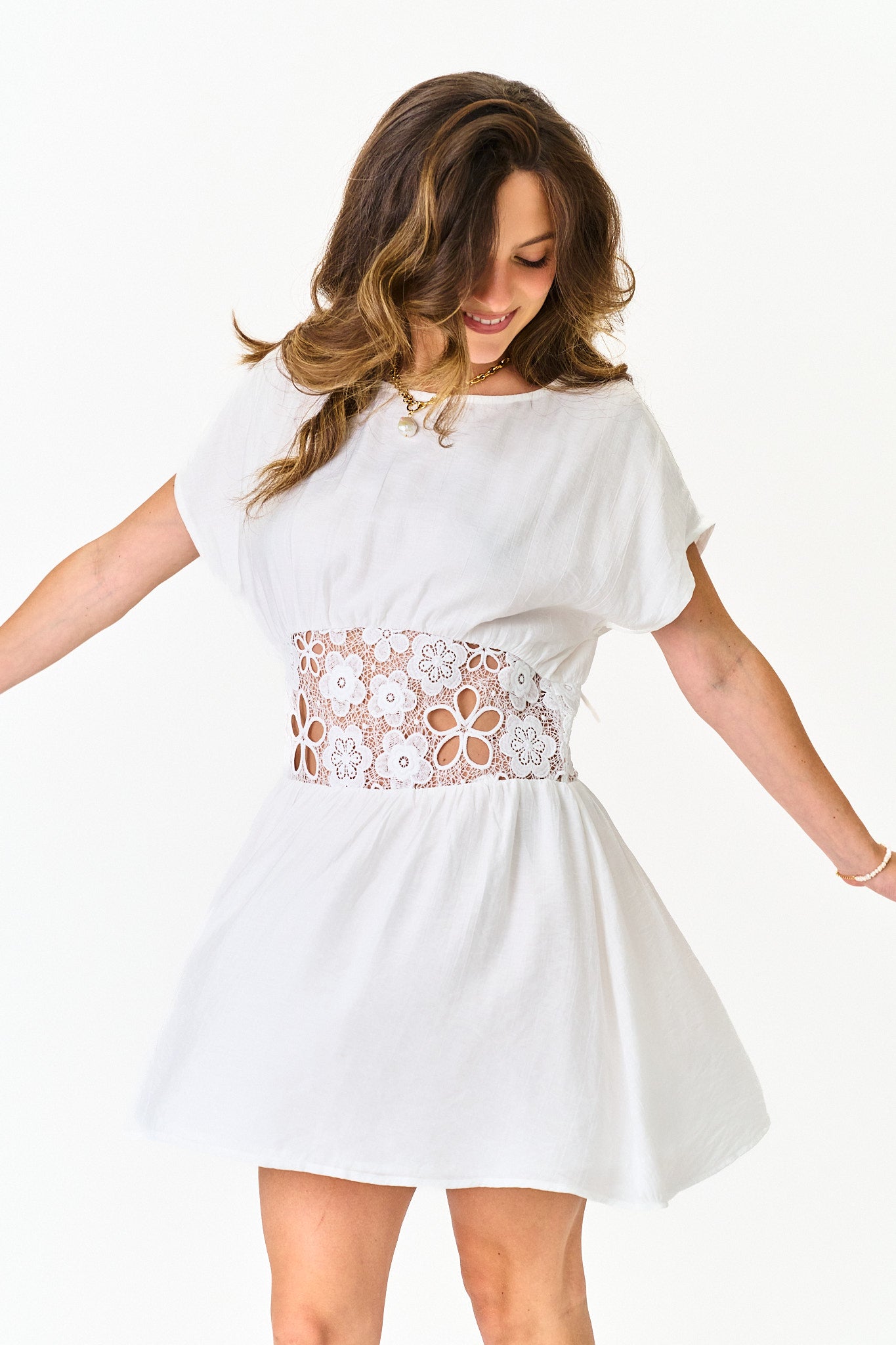 Woman wearing a white dress with a floral belt on a white background
