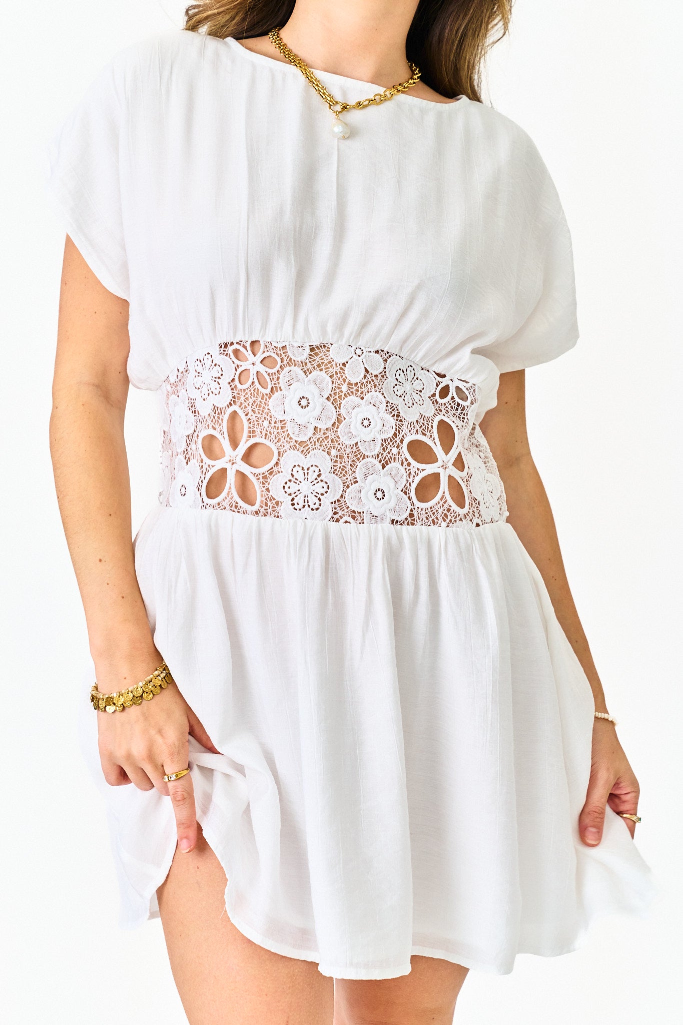White dress with floral lace detail on a plain background