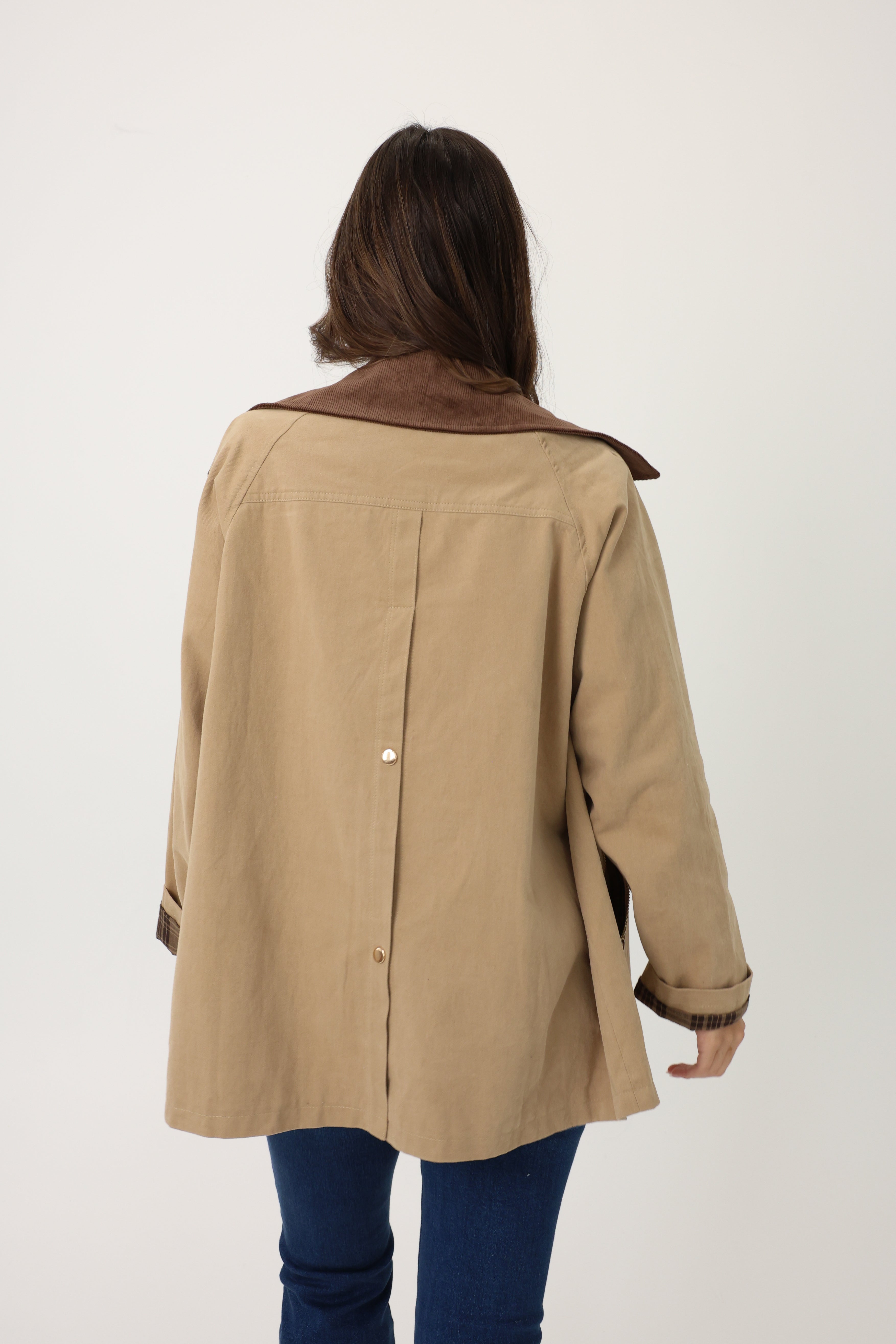 Person wearing a beige coat with brown collar on a white background