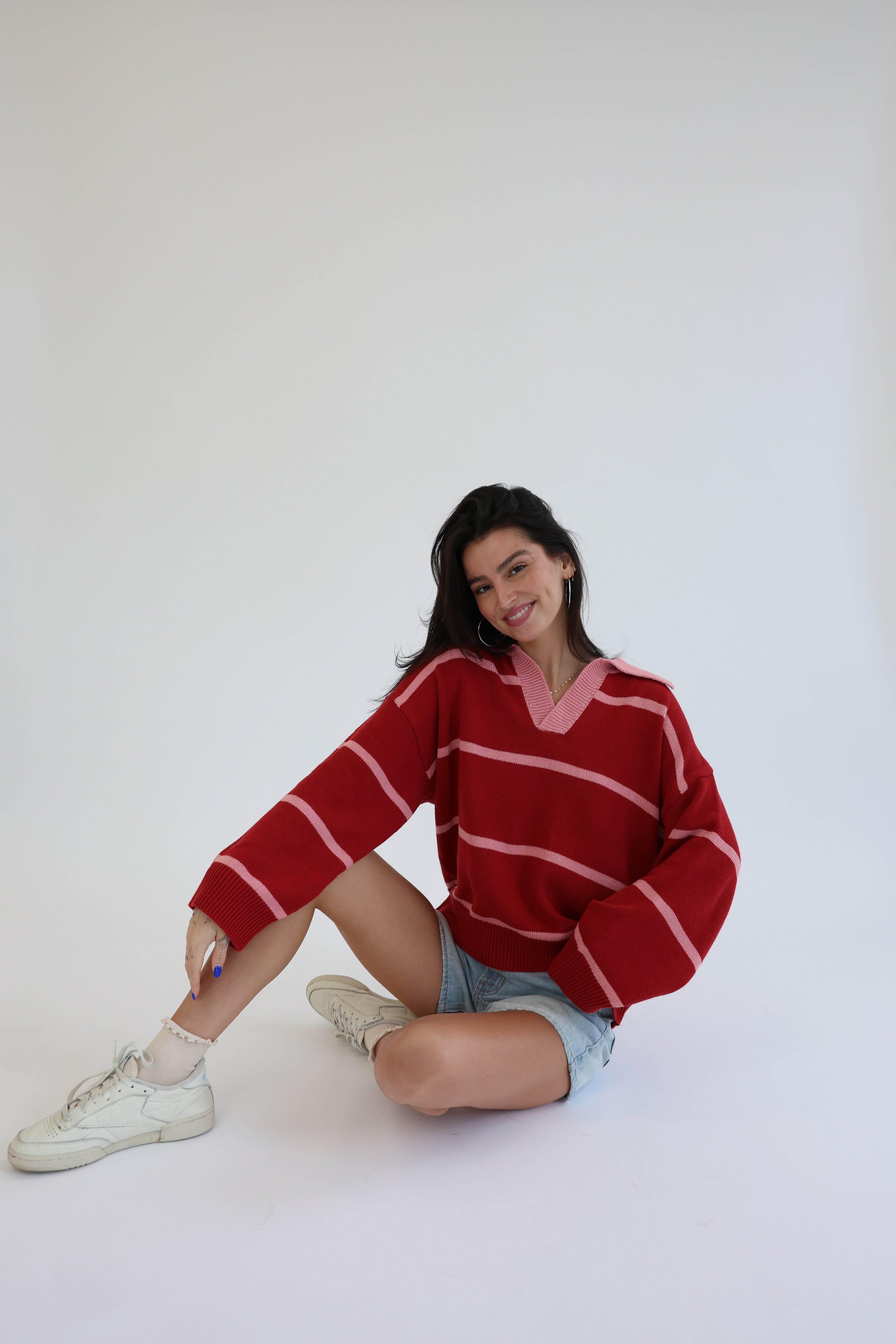 Woman wearing a red striped sweater sitting on a white background