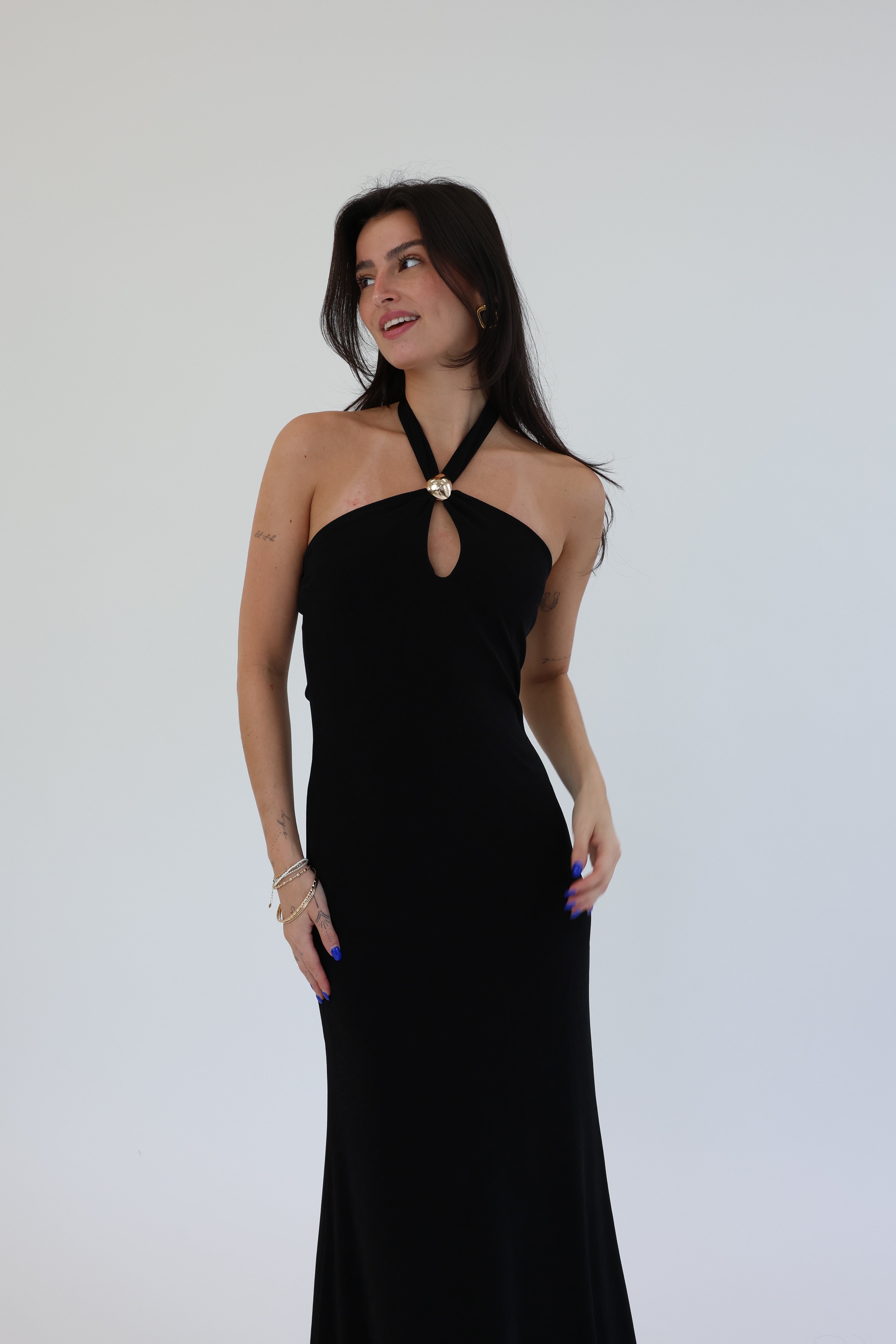 Woman wearing a black halter neck dress against a plain background