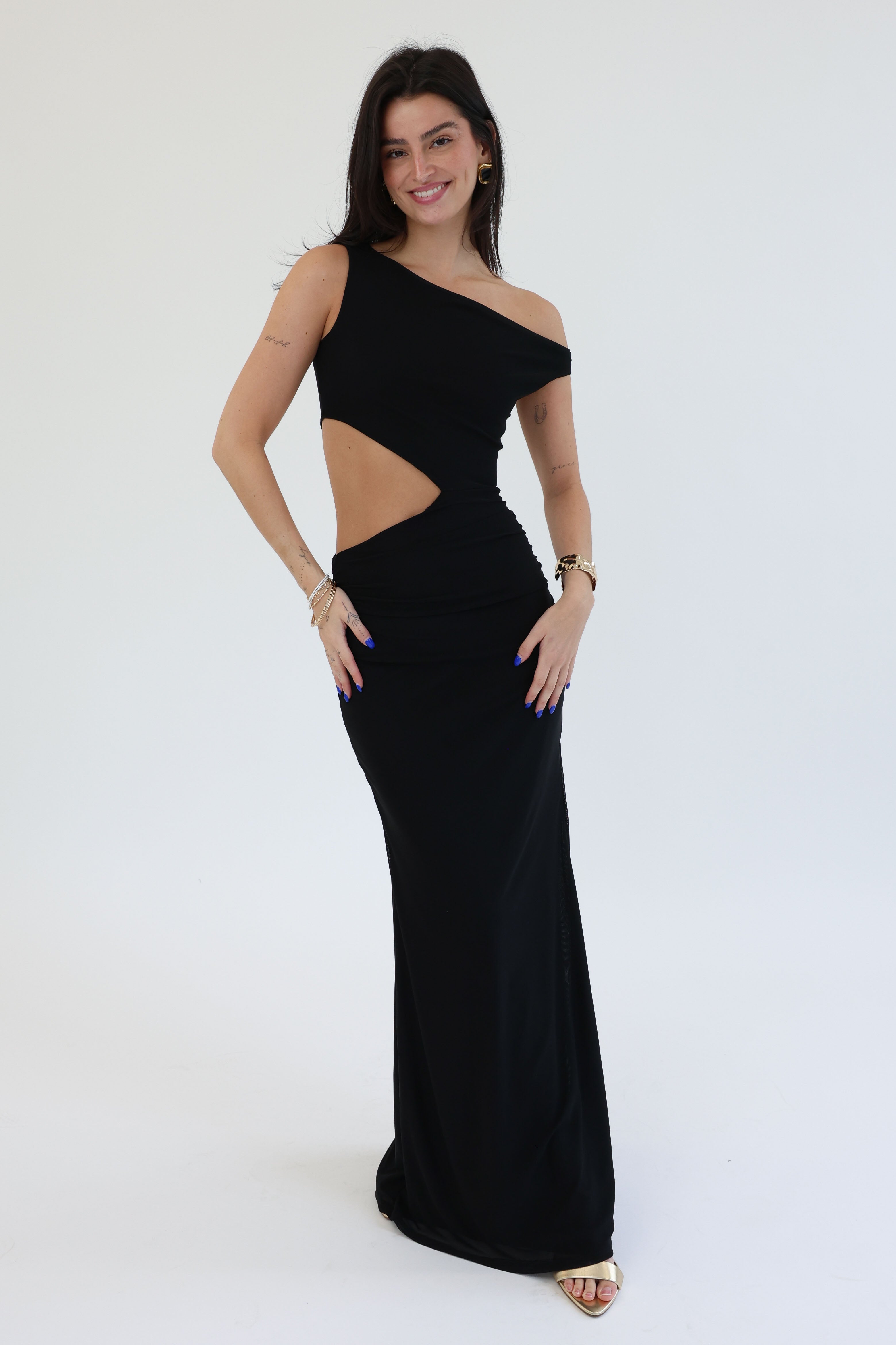Woman wearing a black one-shoulder evening gown with cut-out design on a white background