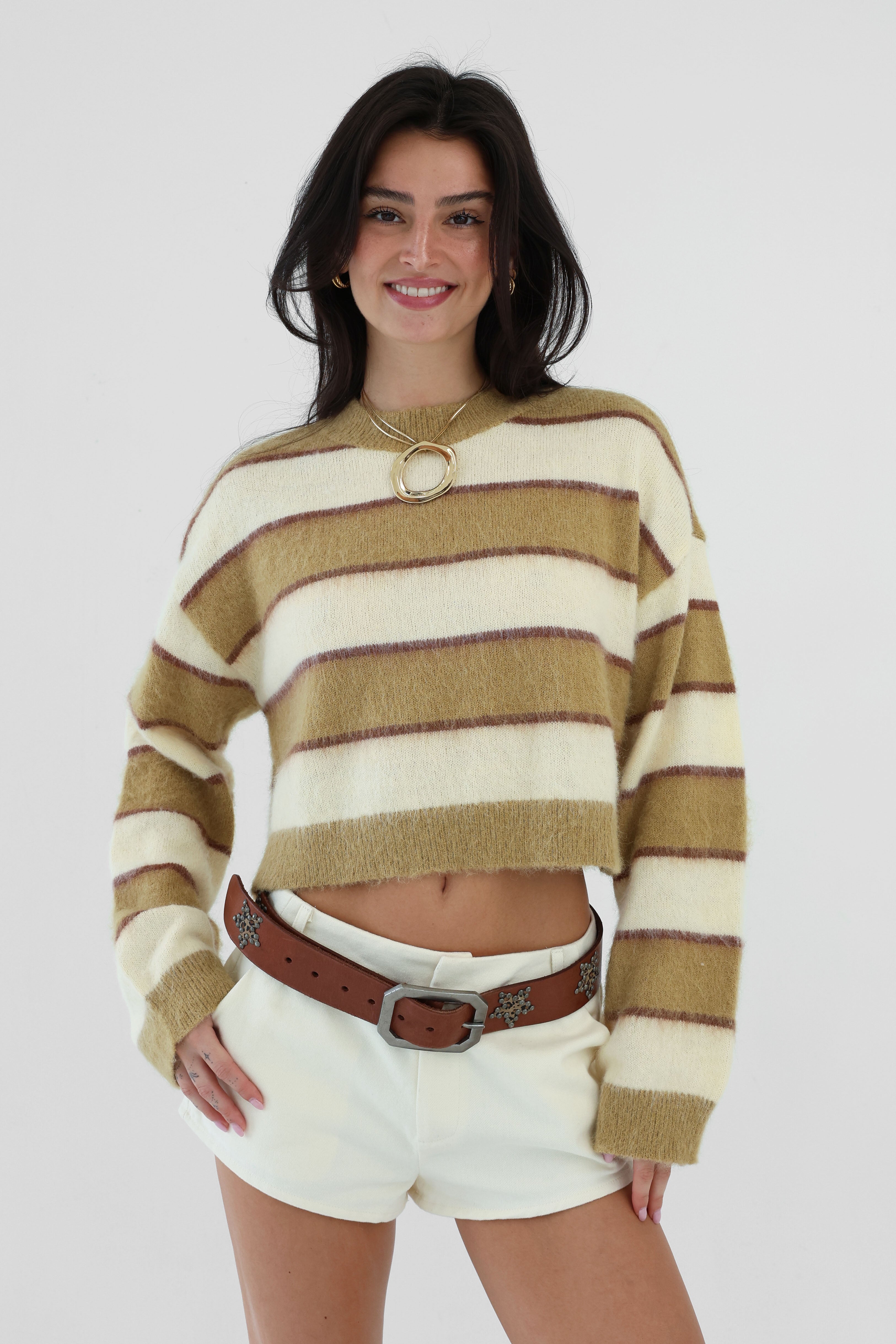 Woman wearing a striped sweater and white shorts on a plain background