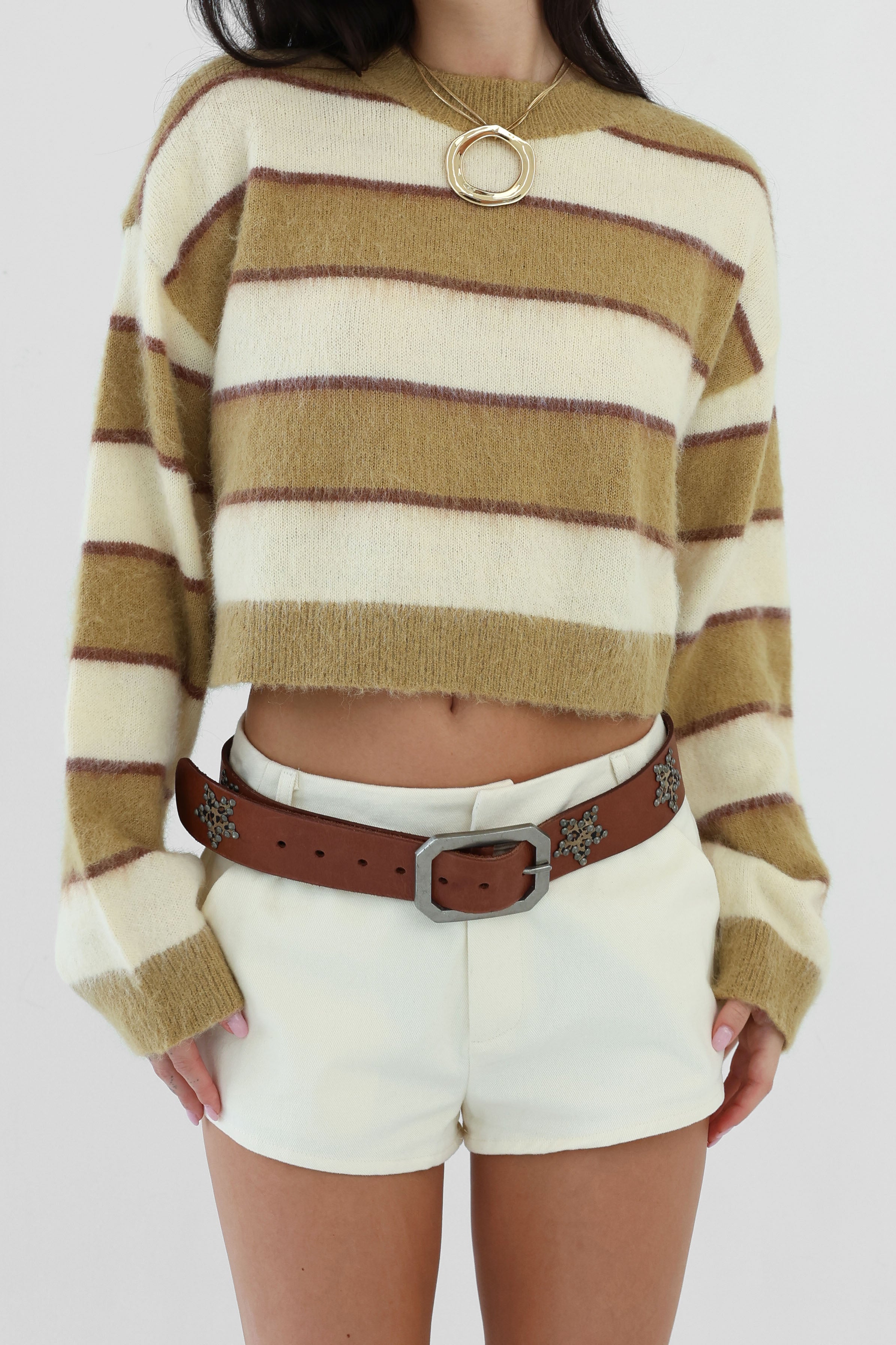 Person wearing a striped sweater and white shorts with a brown belt.