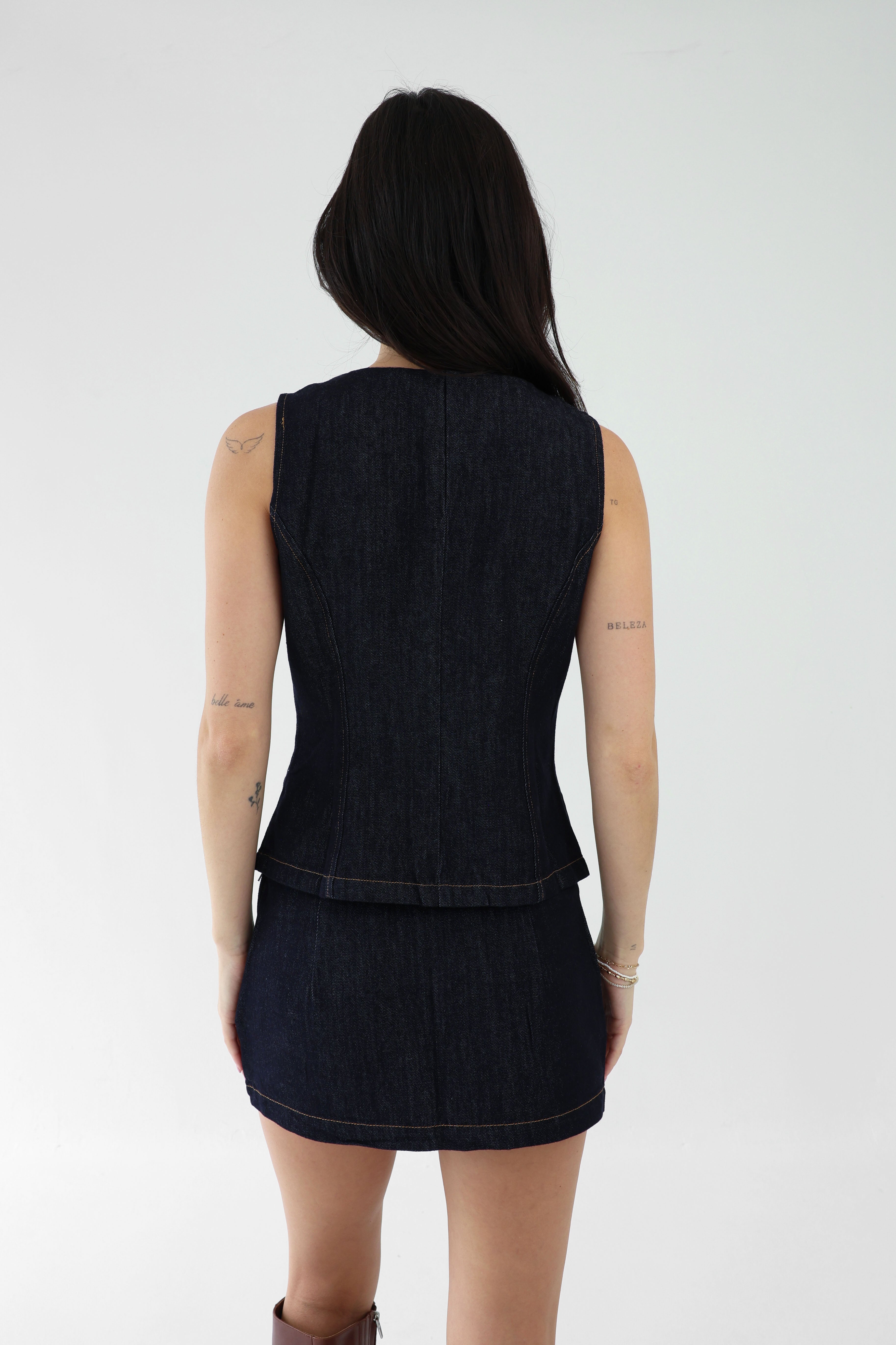 Person wearing a black sleeveless top and skirt set on a white background