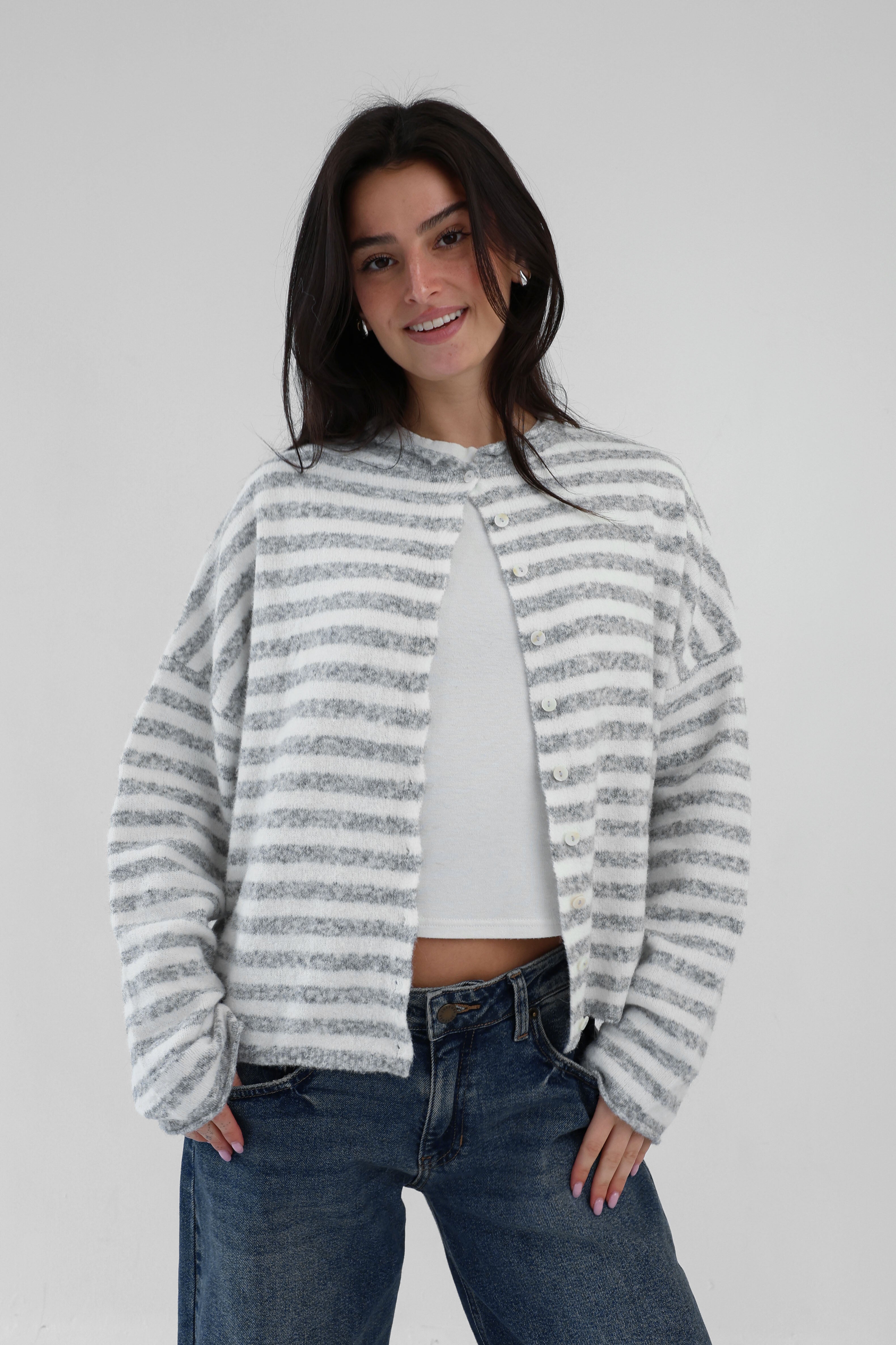 Woman wearing a striped sweater and jeans on a plain background
