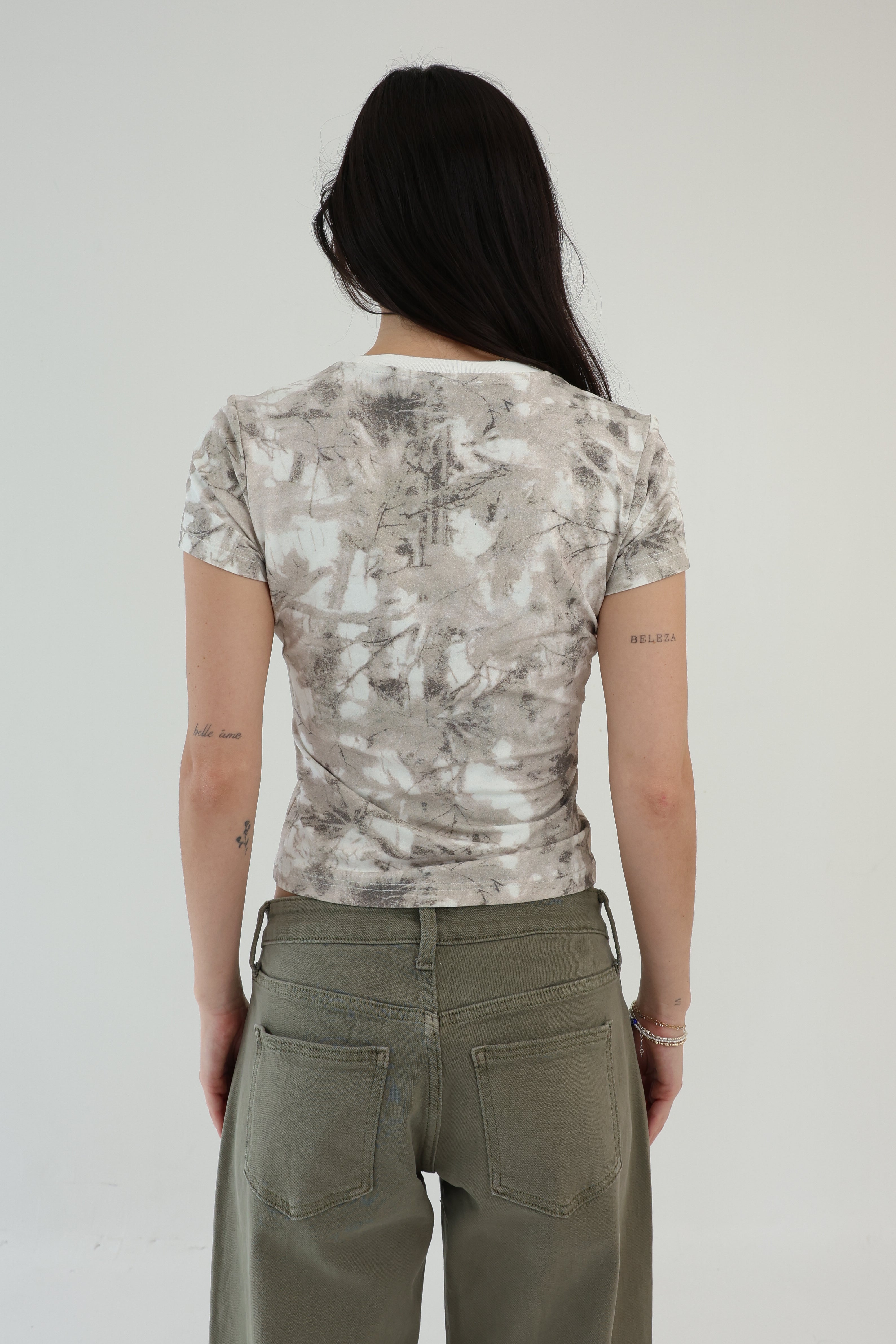 Person wearing a patterned shirt and green pants on a plain background
