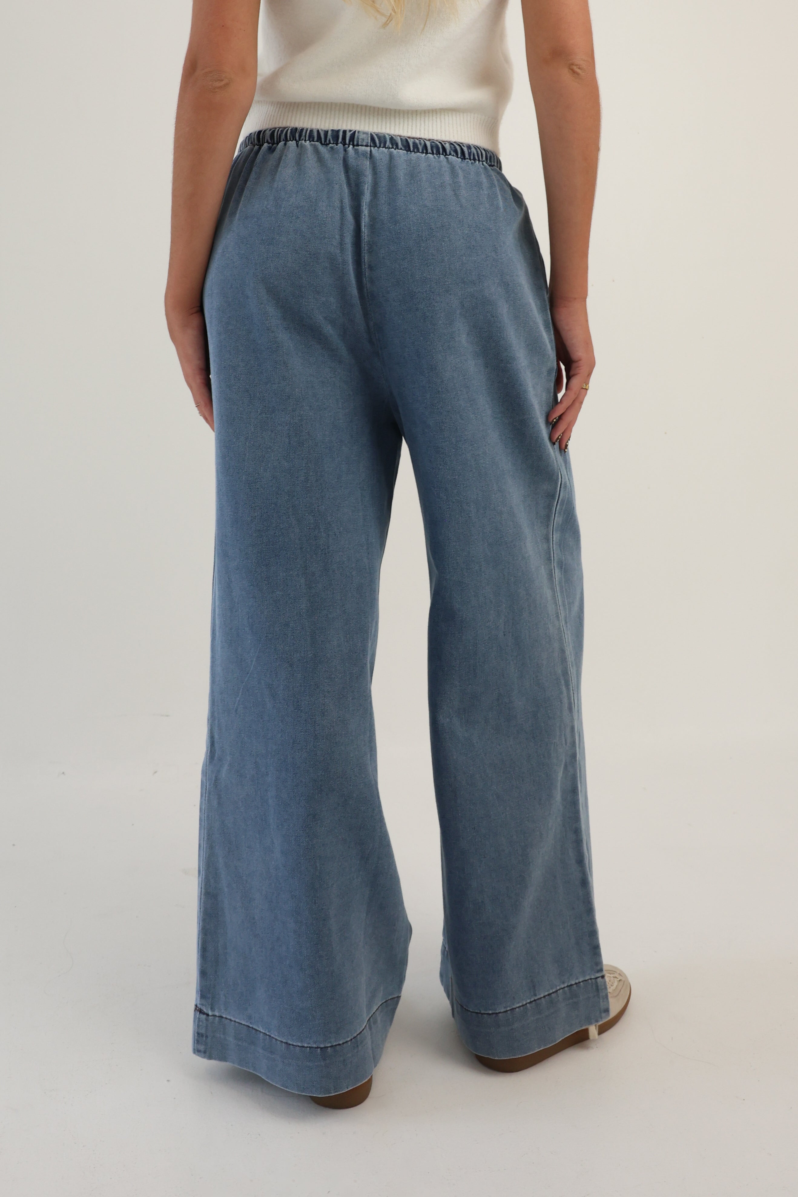 Person wearing blue wide-leg jeans on a plain background