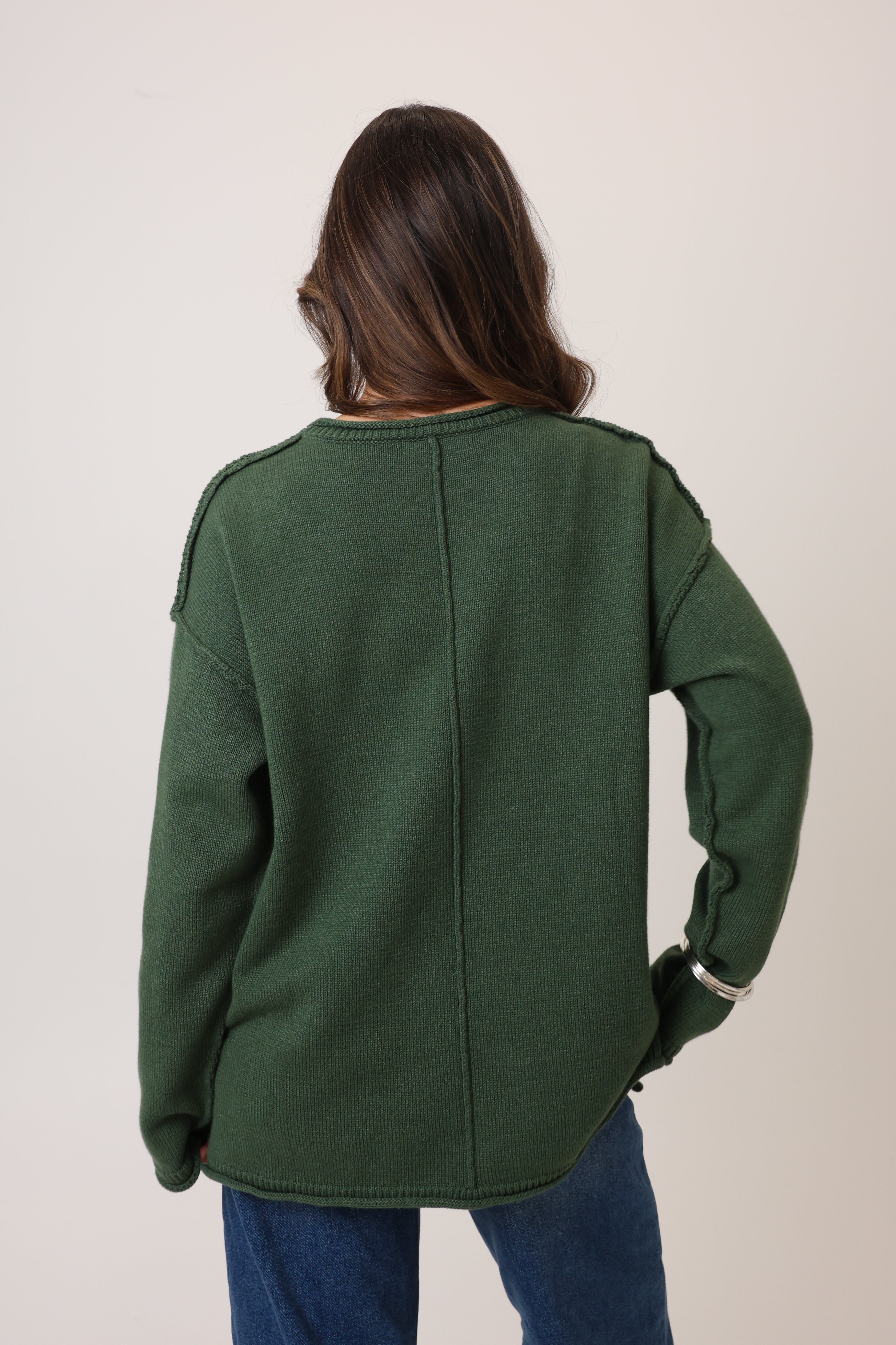 Person wearing a green jacket from behind on a plain background