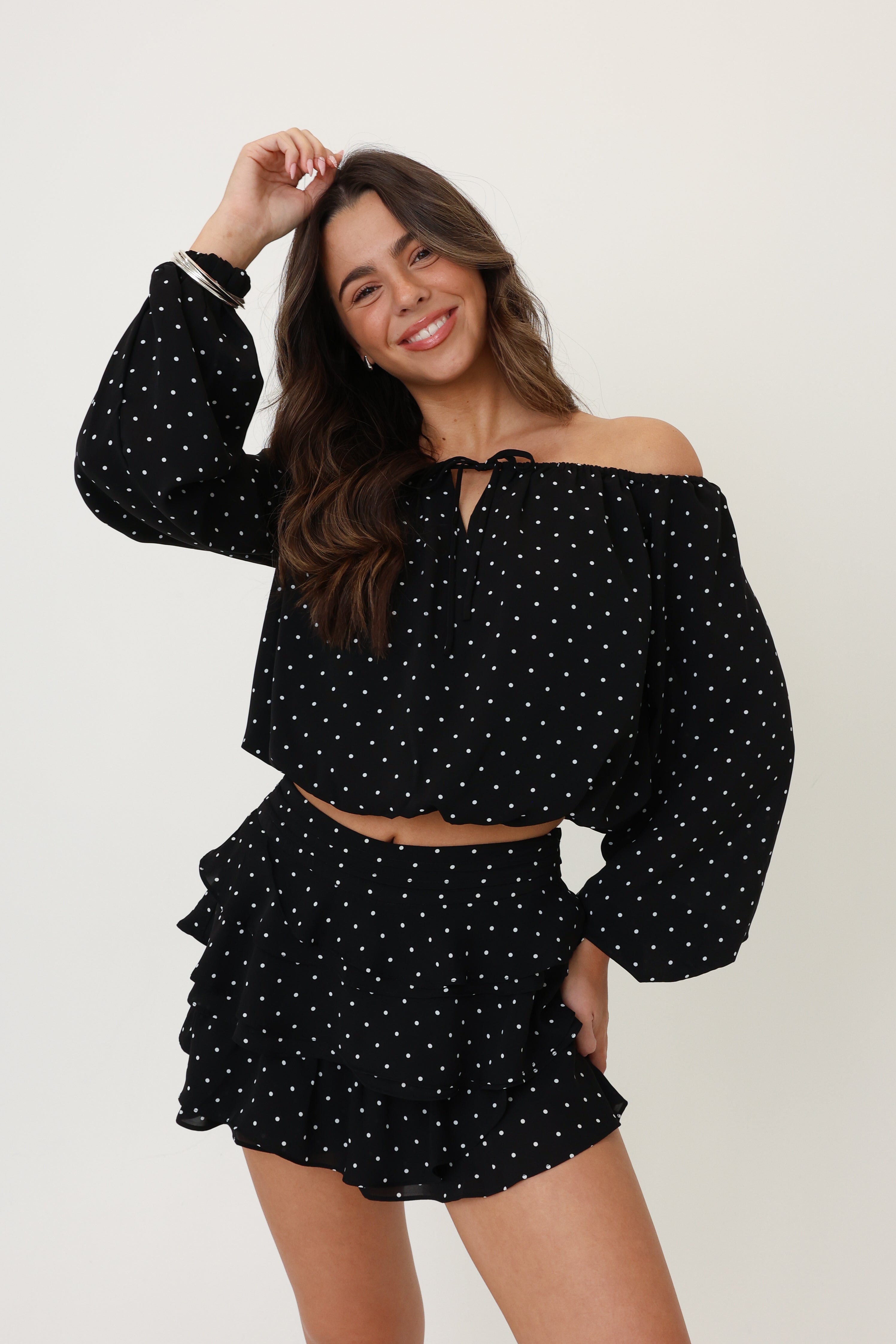 Woman wearing a black polka dot outfit on a white background