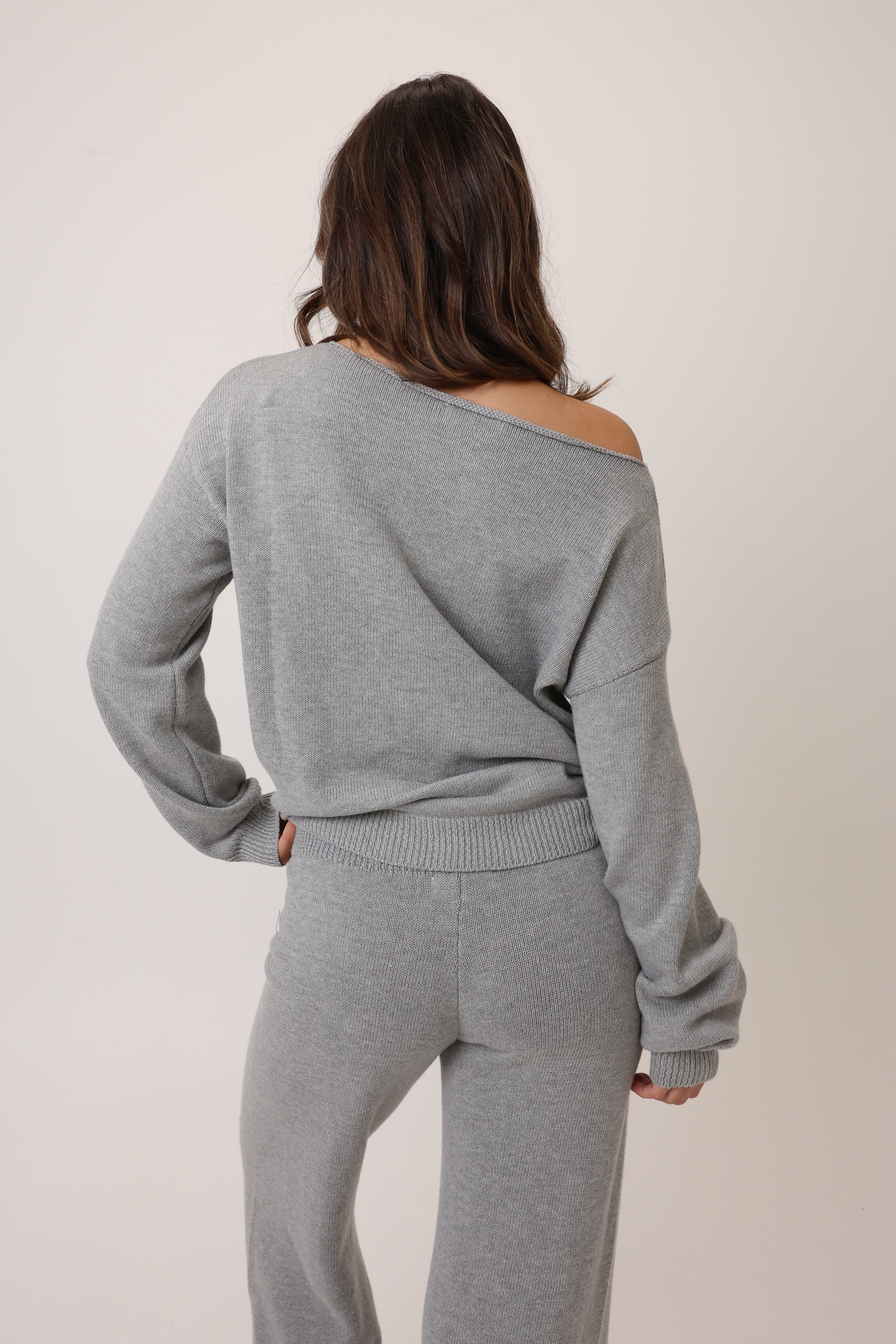 Woman wearing a gray off-shoulder top and matching pants against a plain background