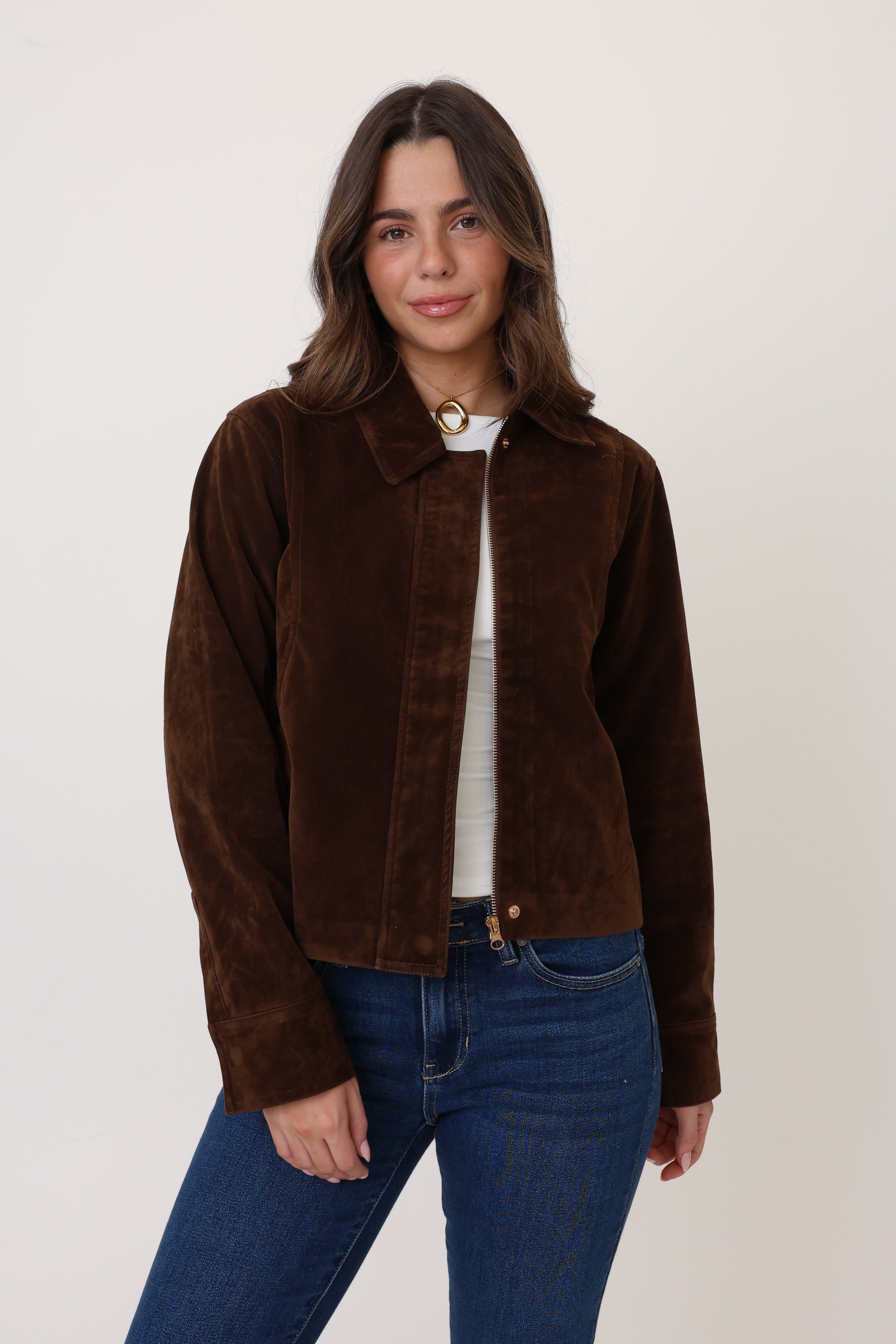 Woman wearing a brown jacket and blue jeans on a white background