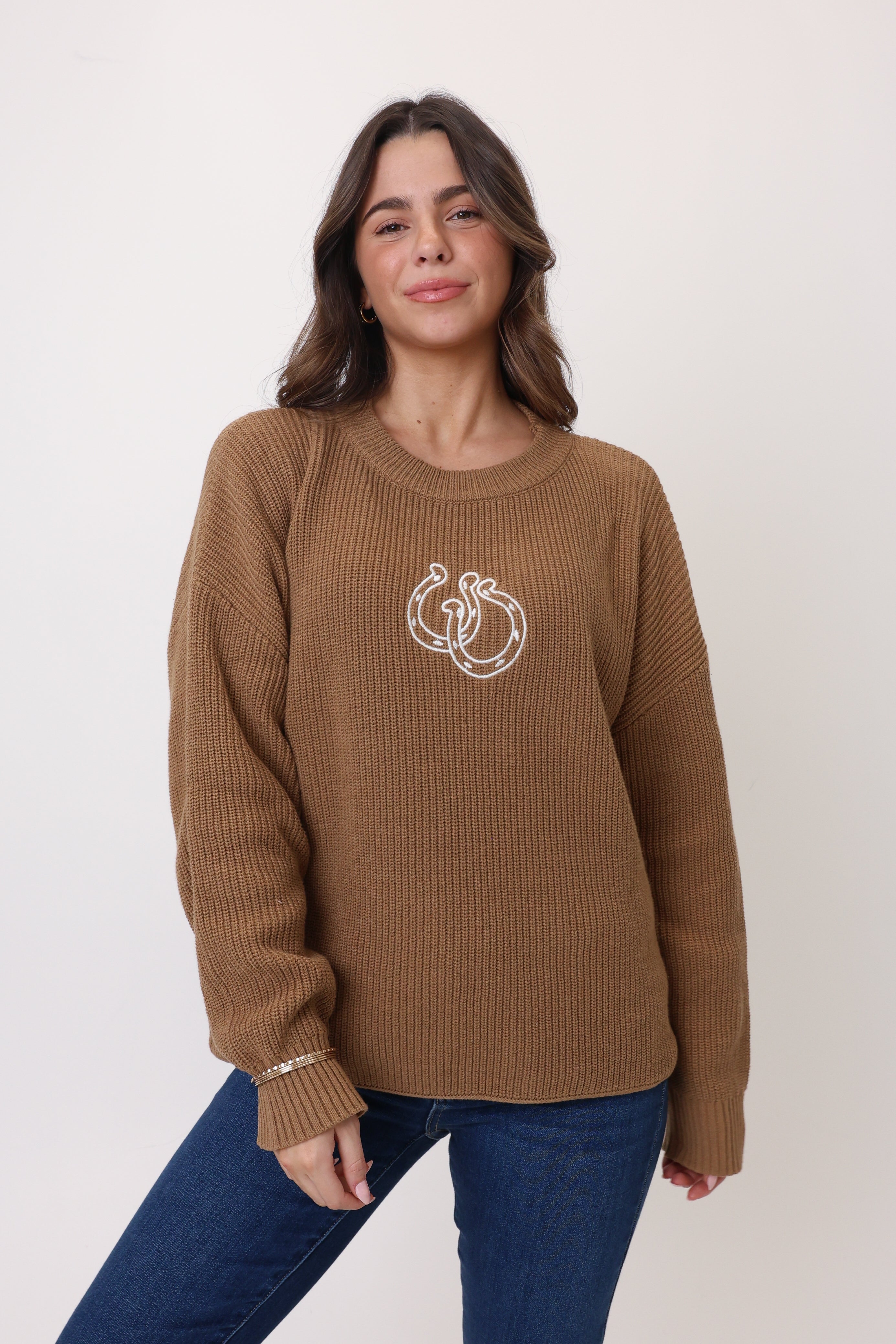 Woman wearing a brown sweater with a logo on a white background