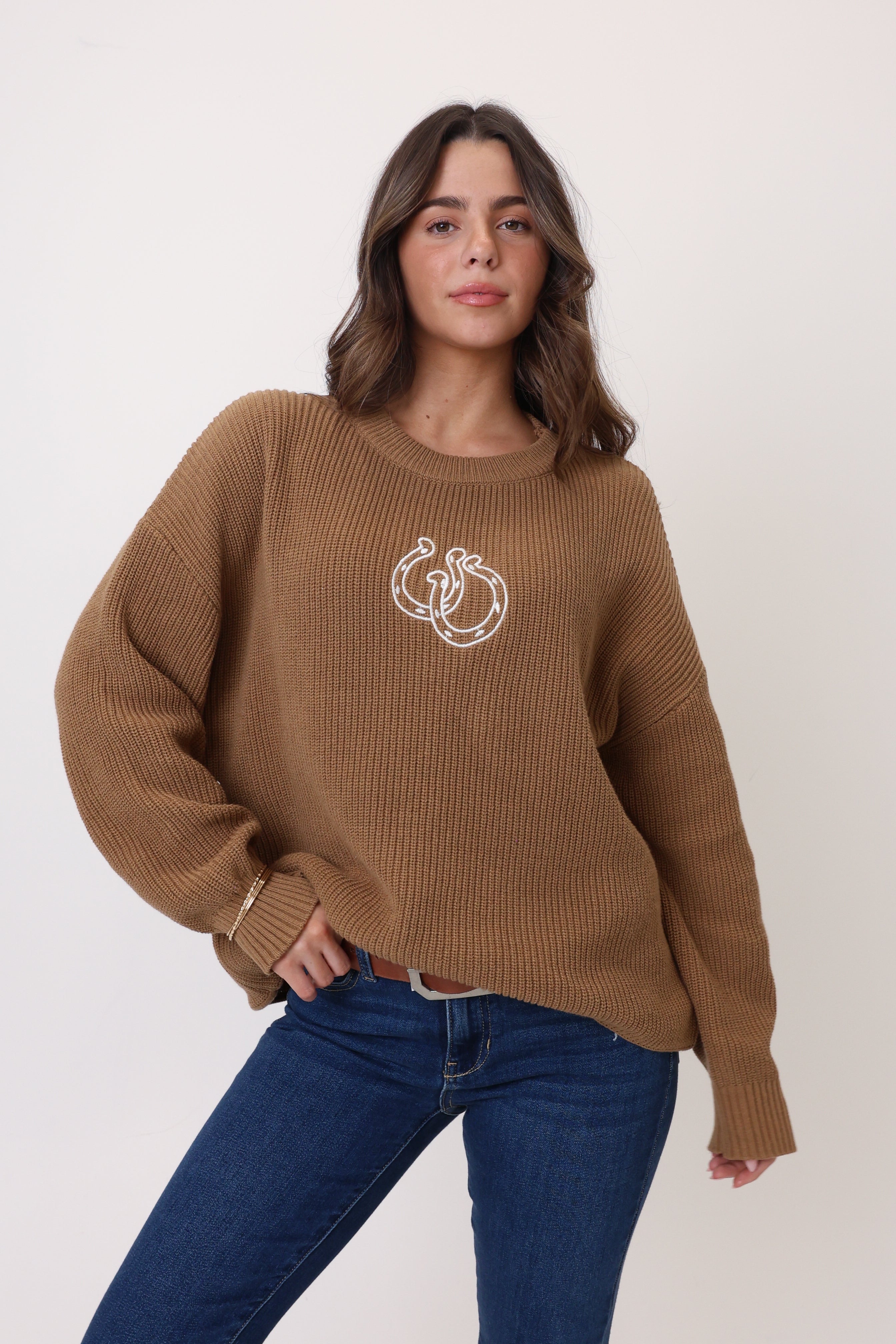 Woman wearing a brown sweater with a logo on a white background