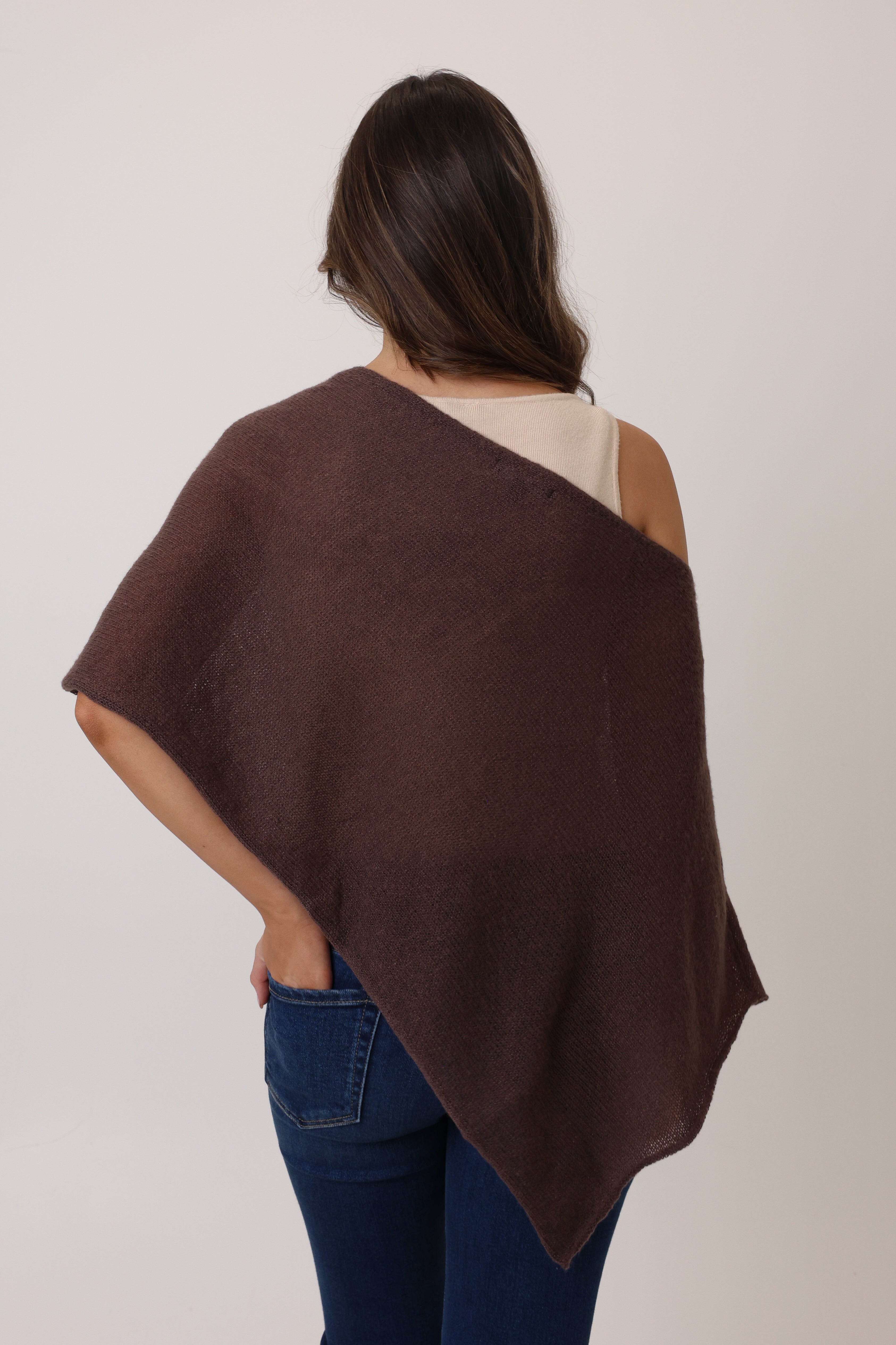 Woman wearing a brown poncho over a plain background