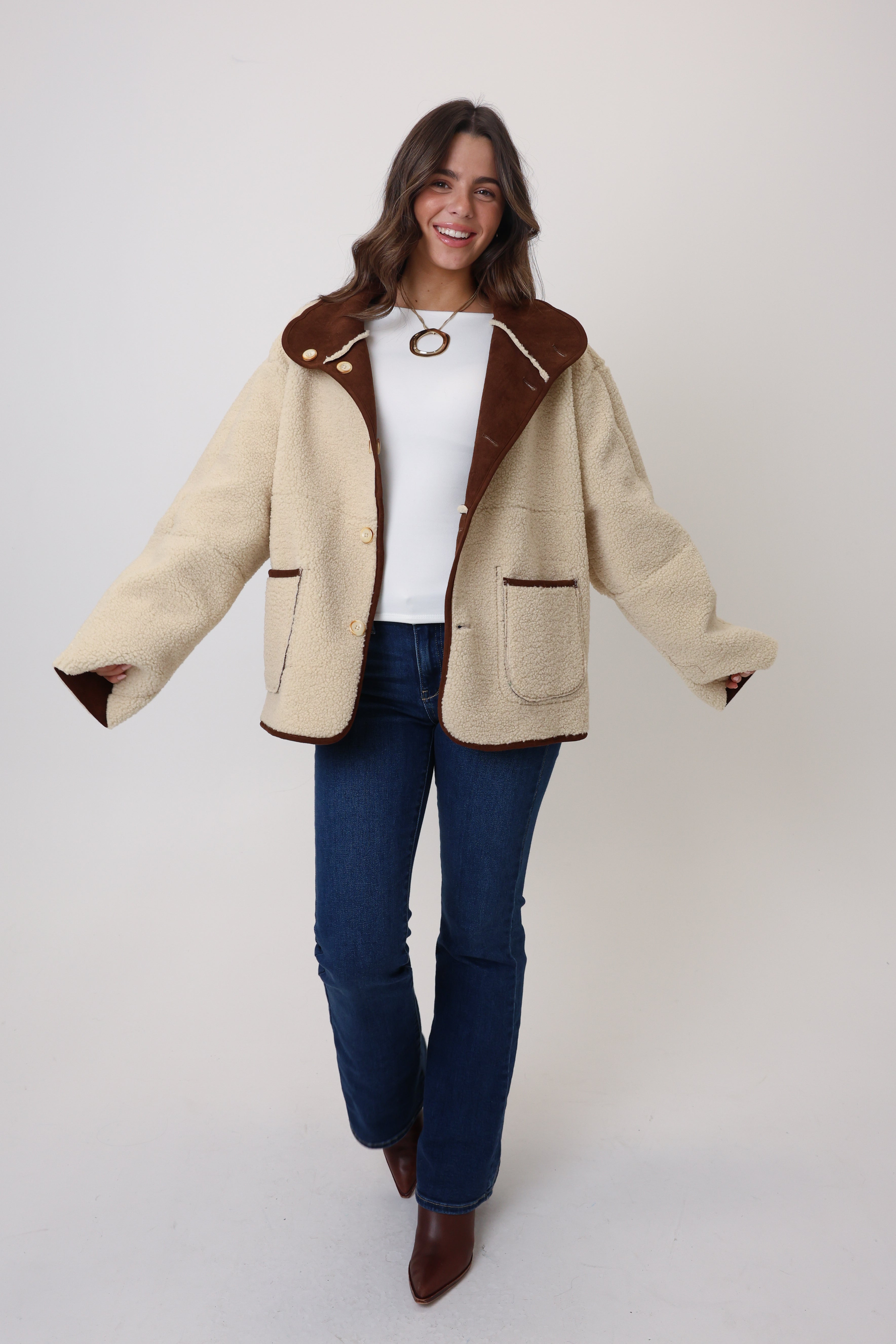 Woman wearing a beige coat with brown trim on a white background
