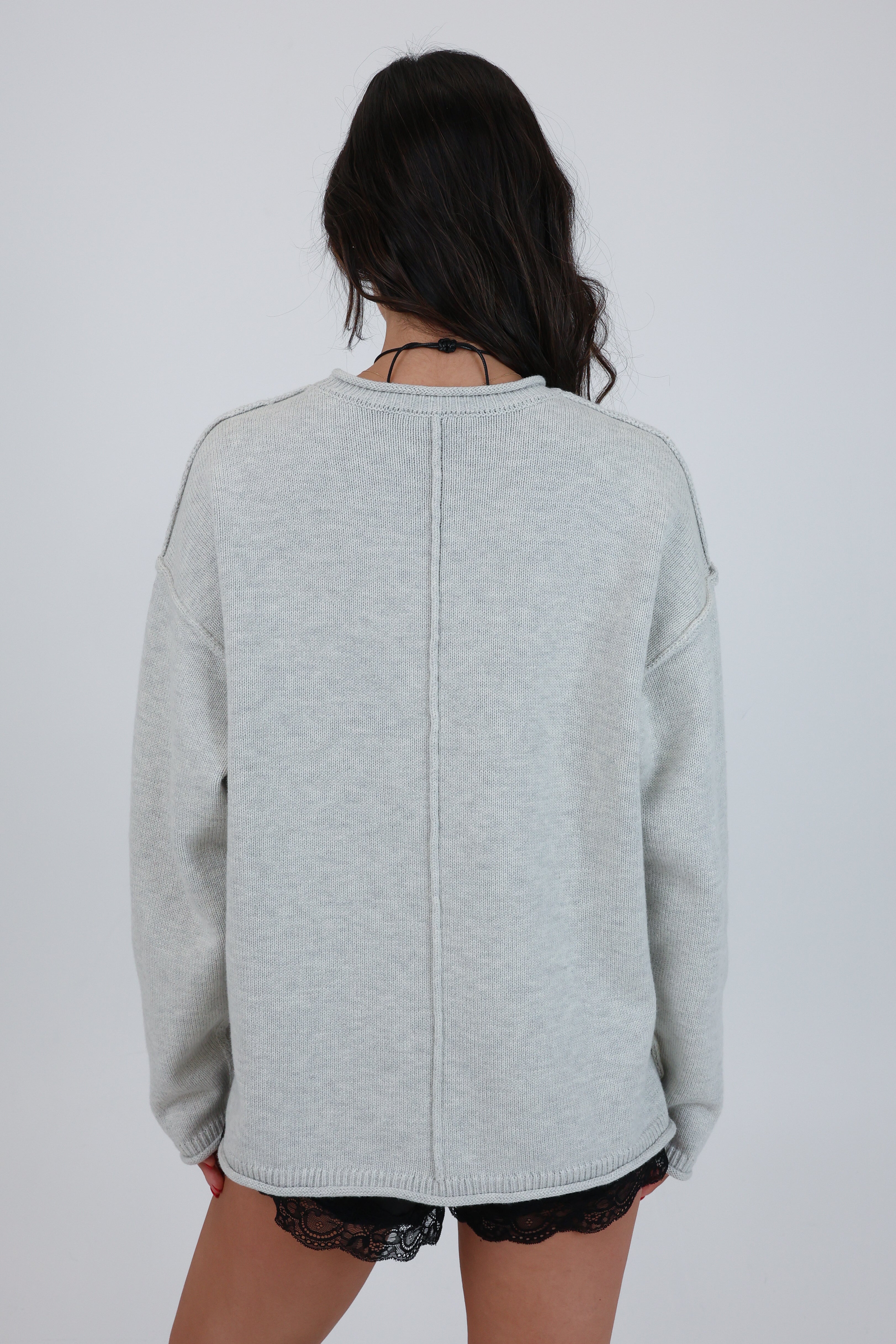 Person wearing a light gray sweater on a plain background