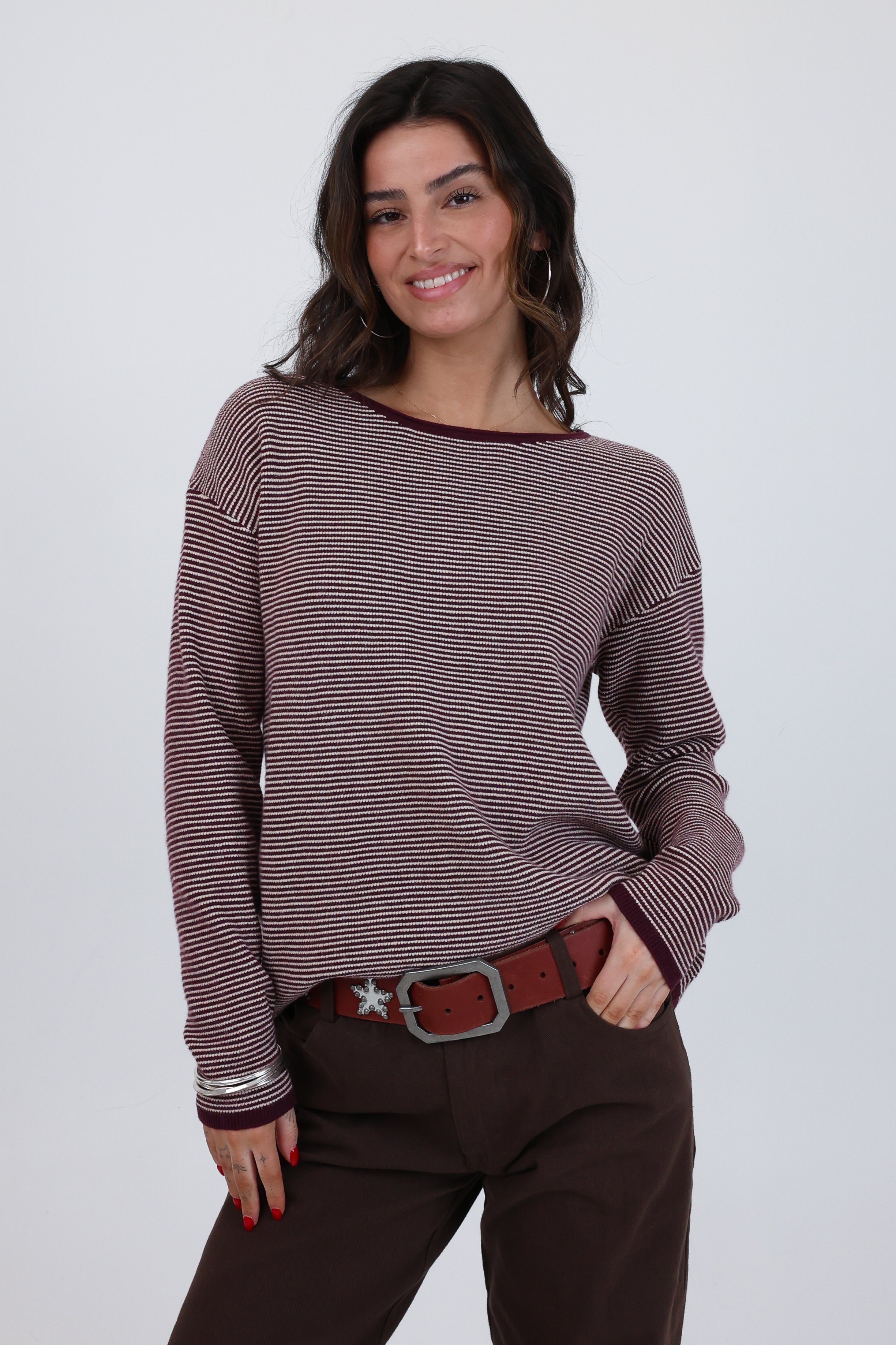 Woman wearing a striped sweater and brown pants against a white background
