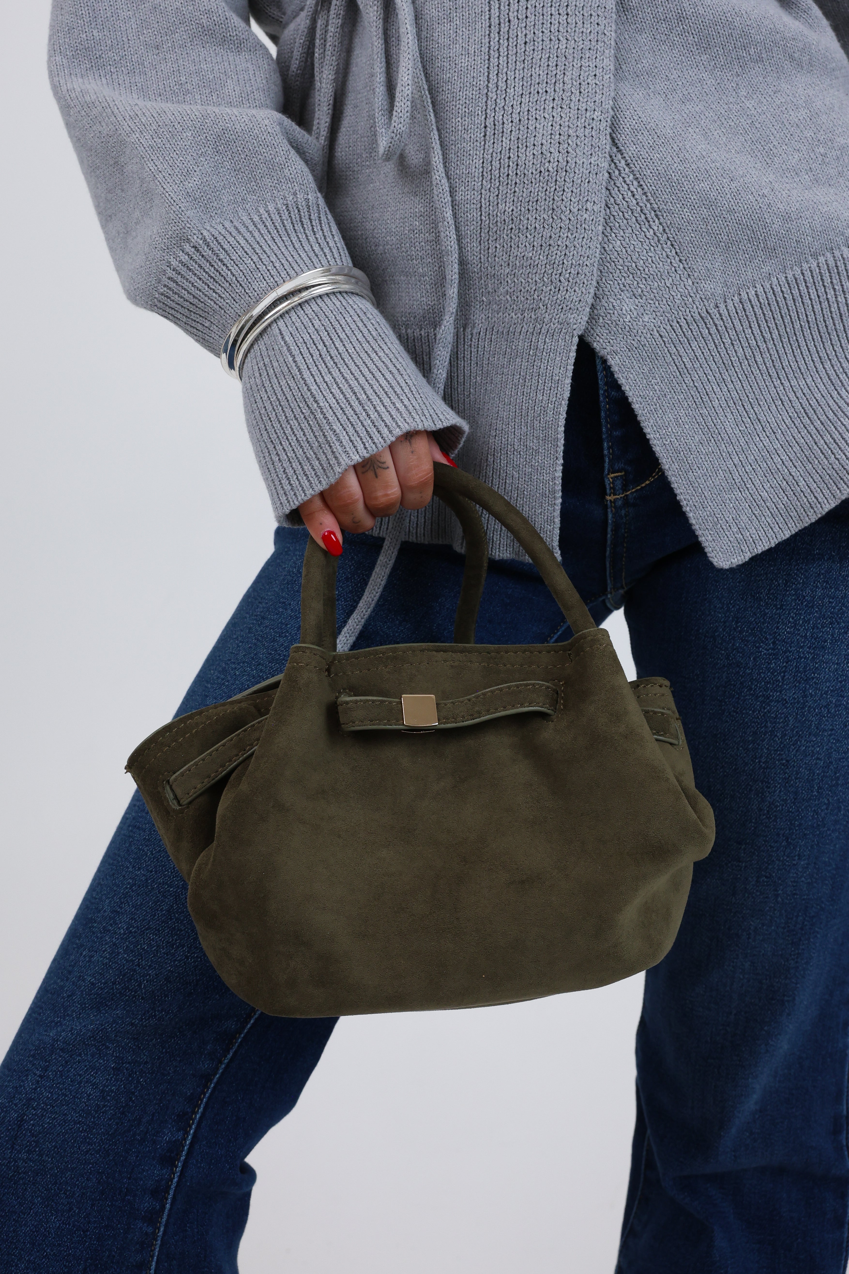 Person holding a green handbag against a plain background