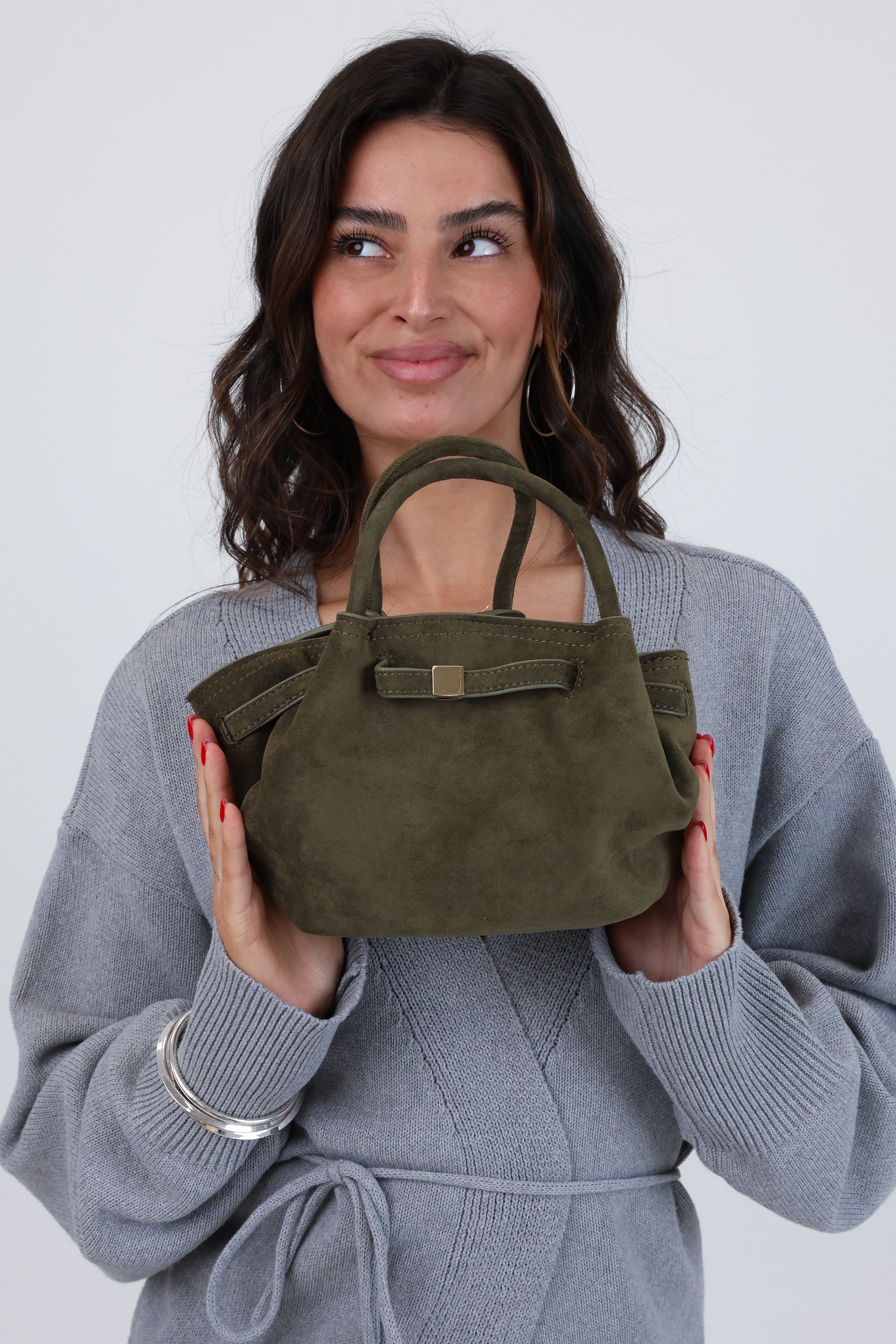 Woman holding a green handbag against a white background