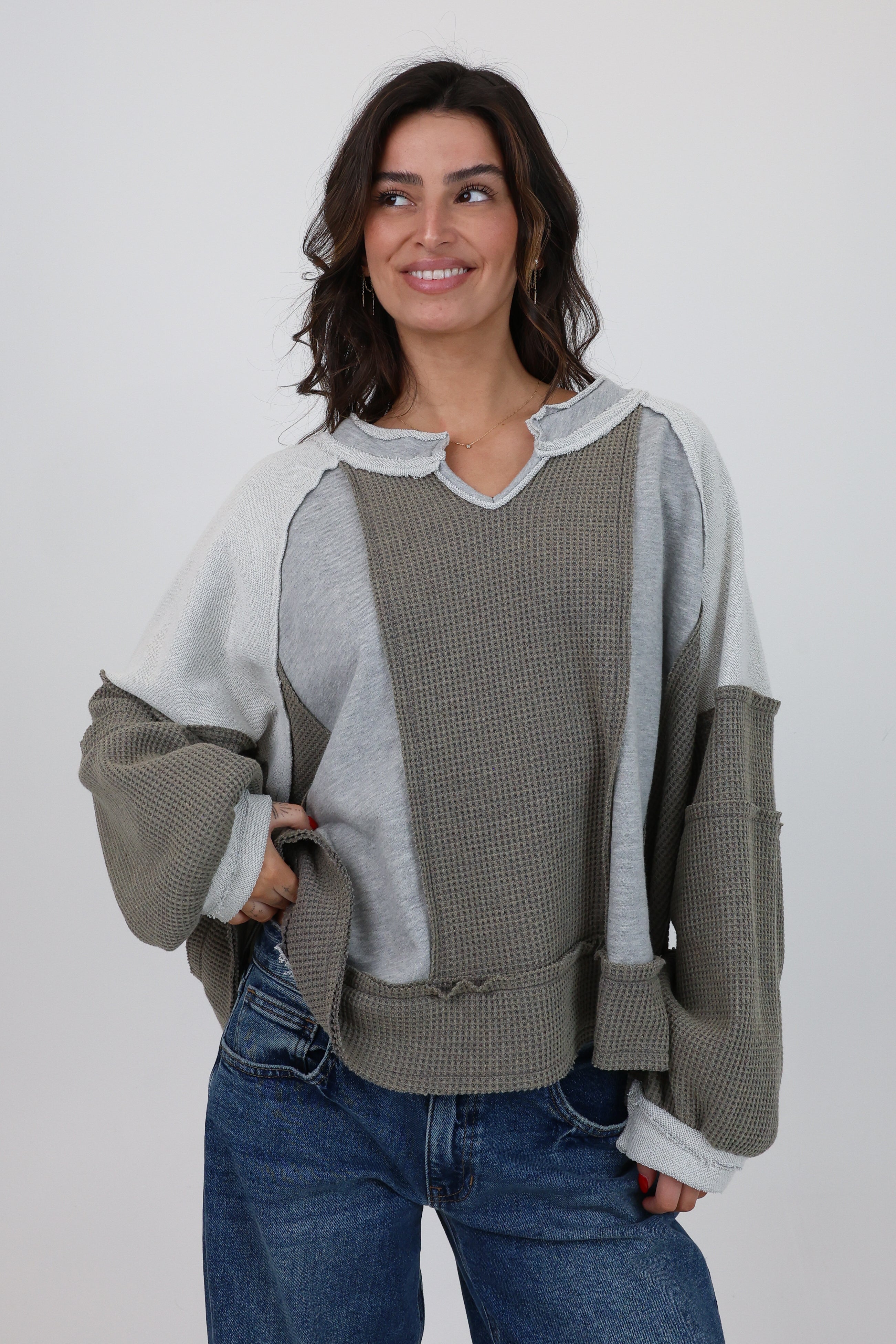 Woman wearing a gray and white sweater with a textured pattern on a white background