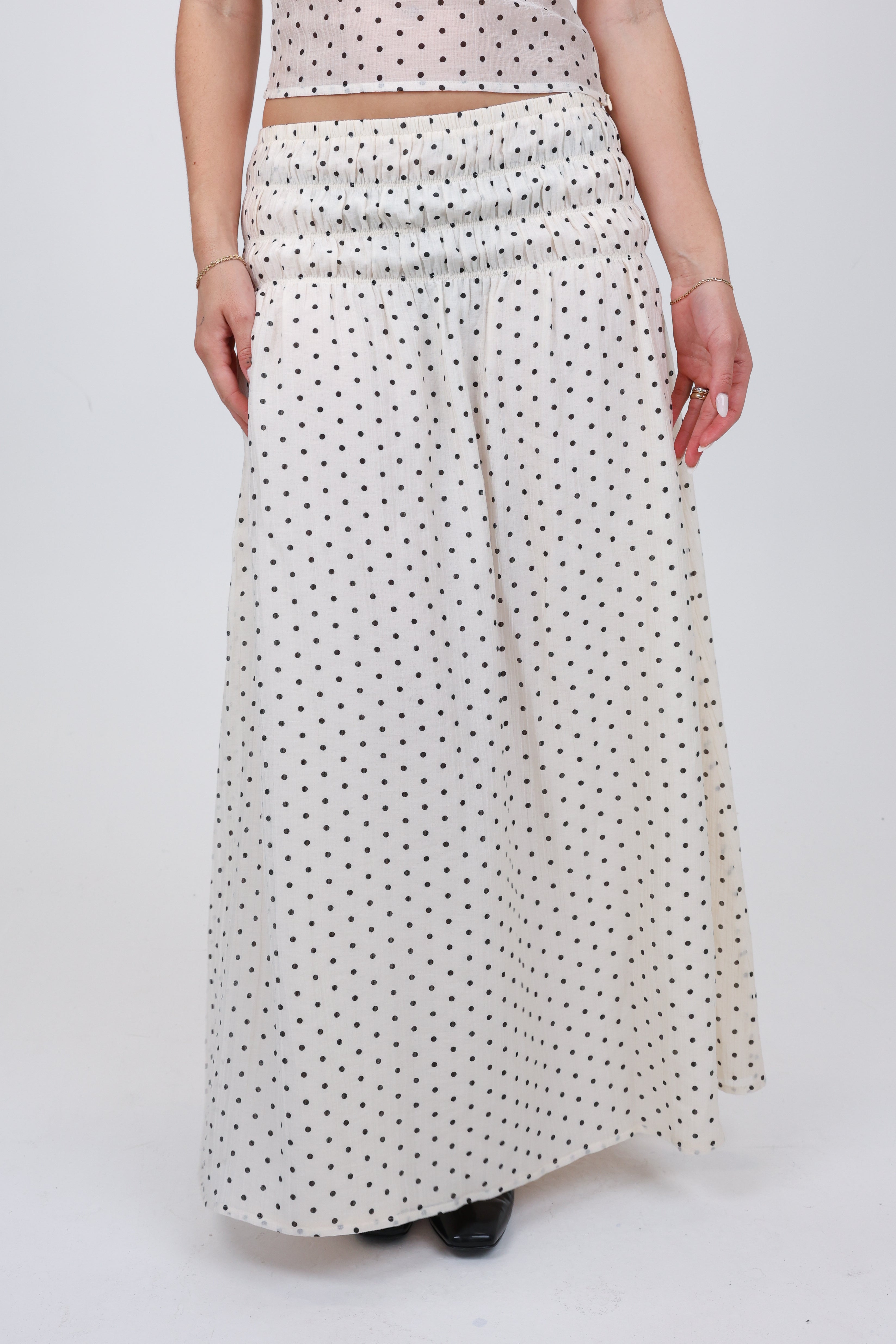 Person wearing a long polka dot skirt on a white background