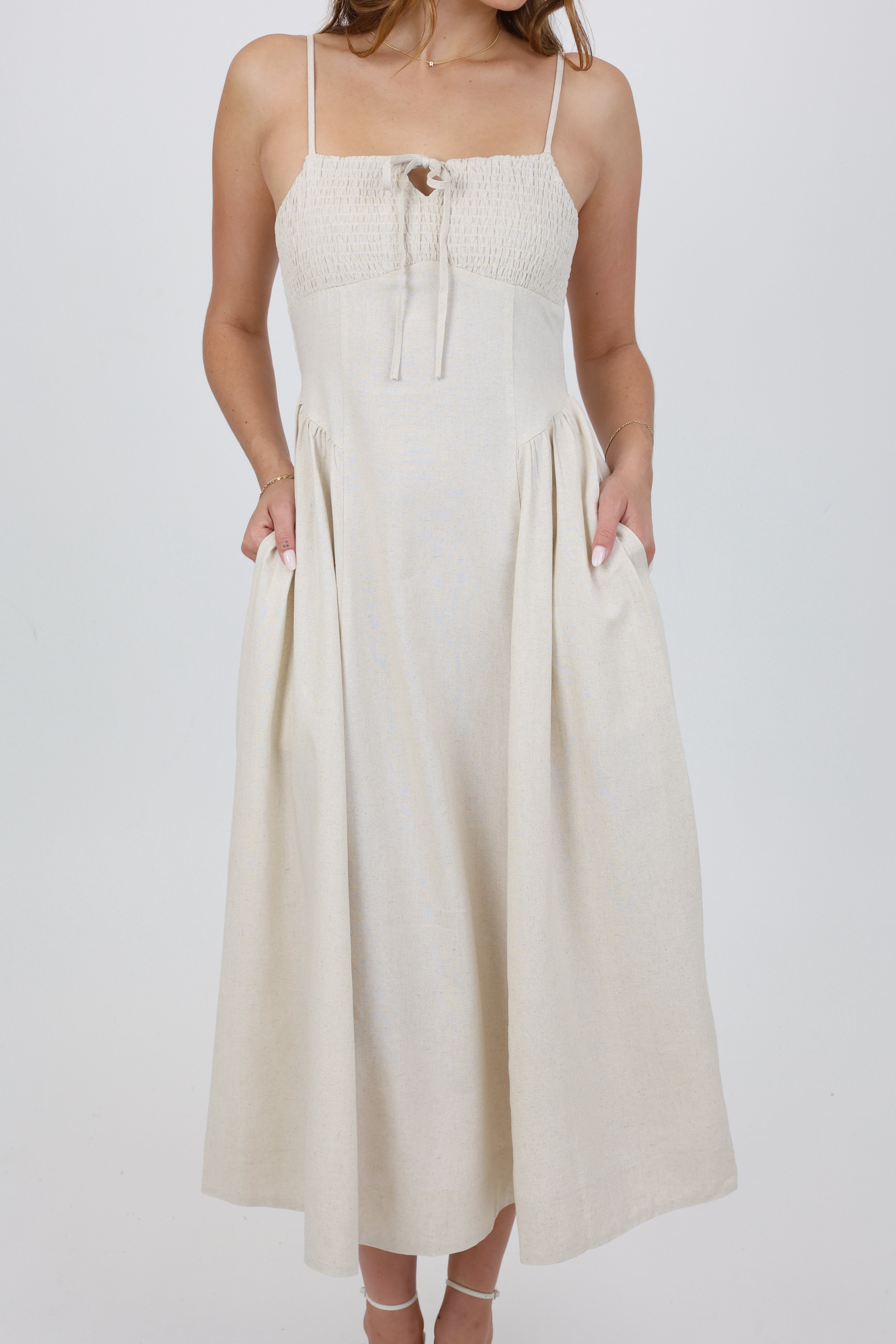 Woman wearing a white dress with thin straps on a plain background