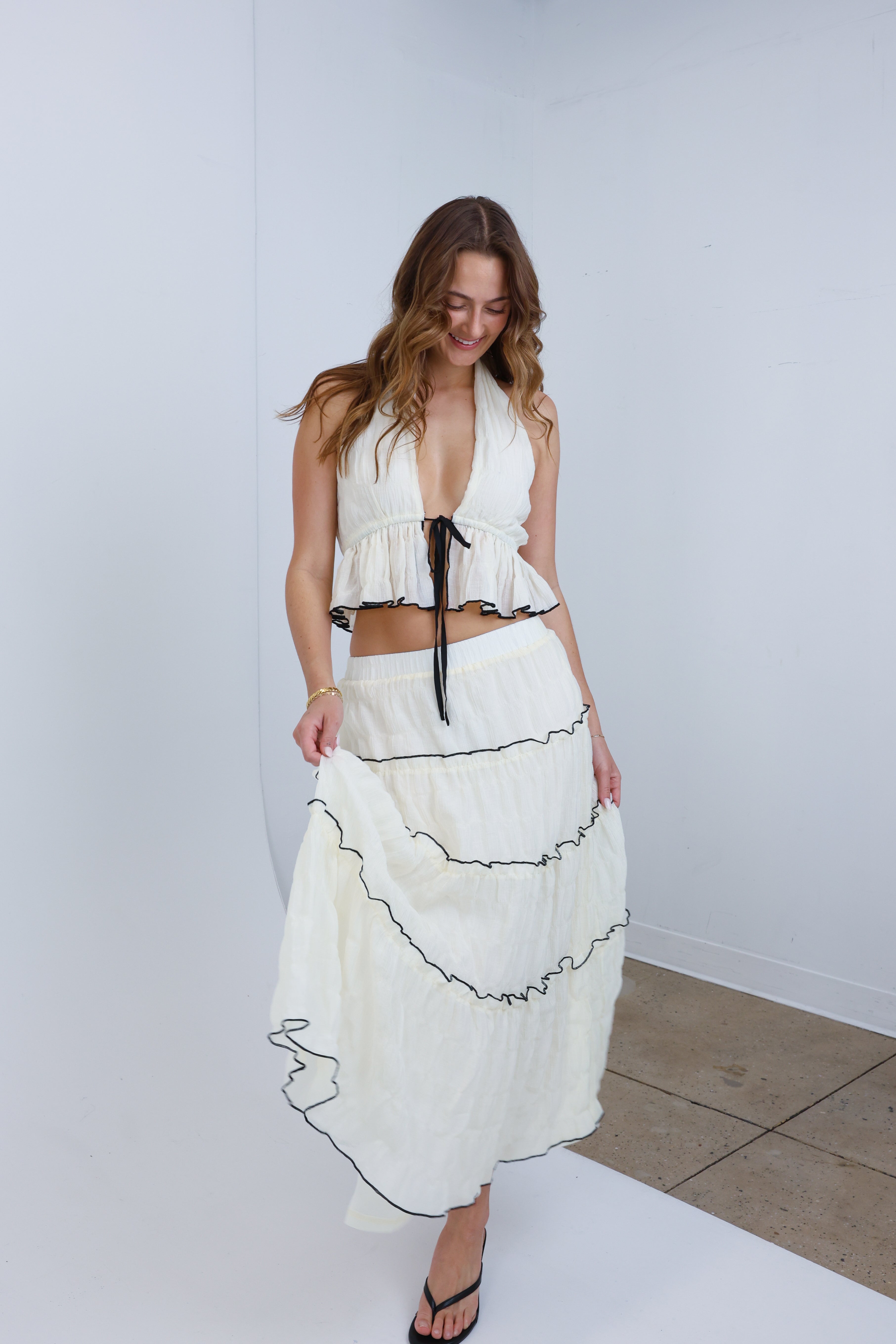 Woman wearing a white dress with black details against a plain background