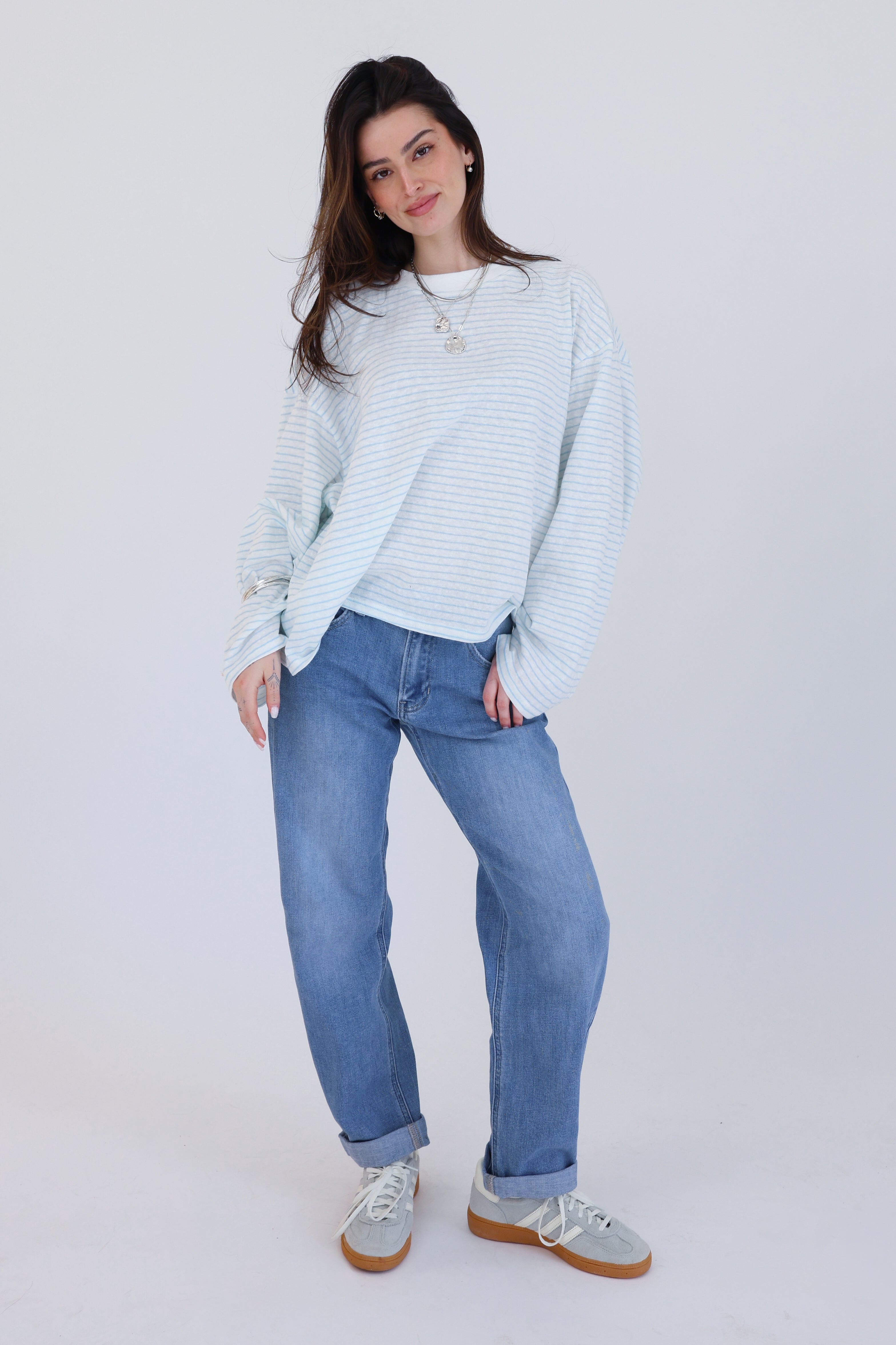 Woman wearing a light blue sweater and jeans on a white background