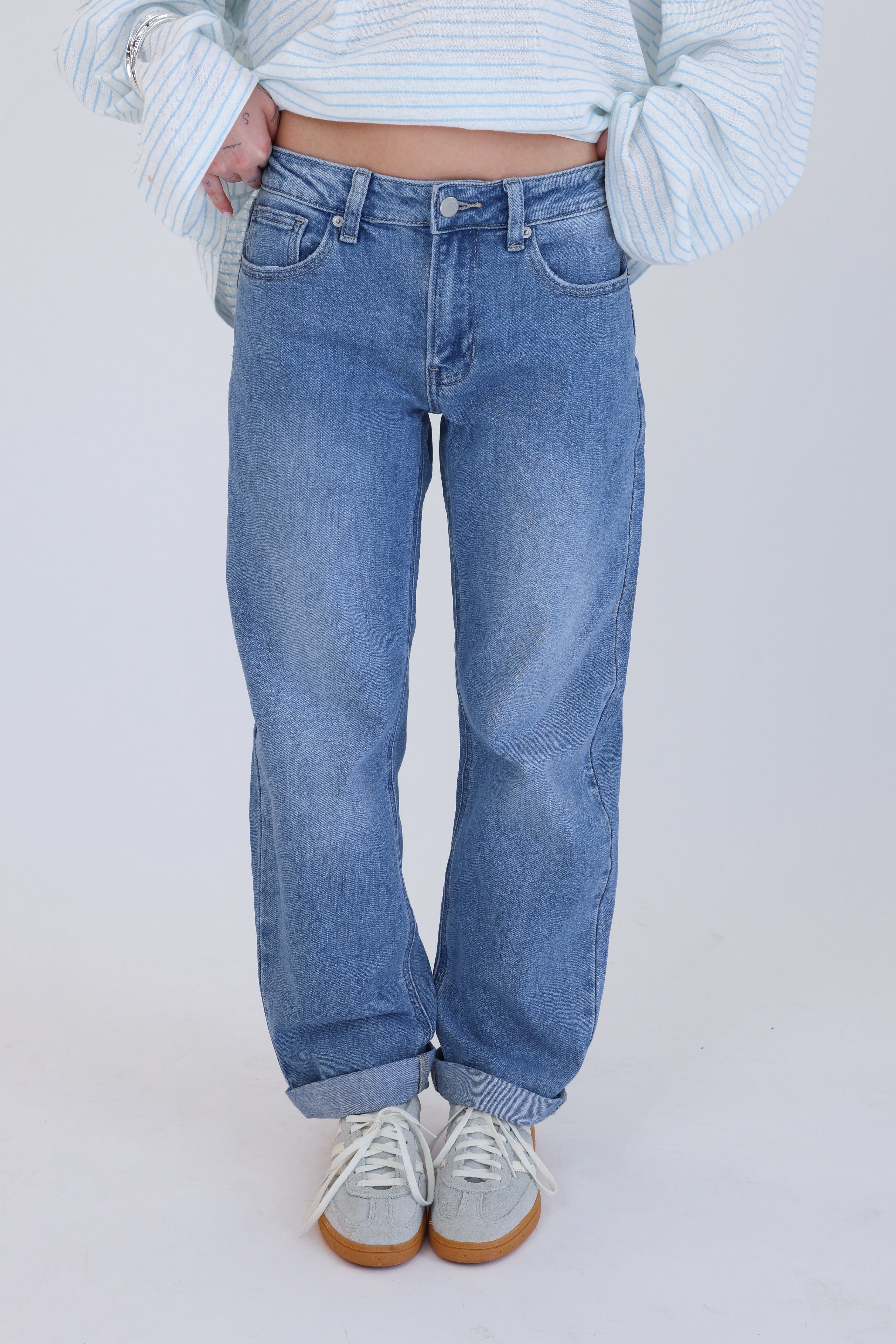 Person wearing light blue jeans and a striped sweater on a plain background