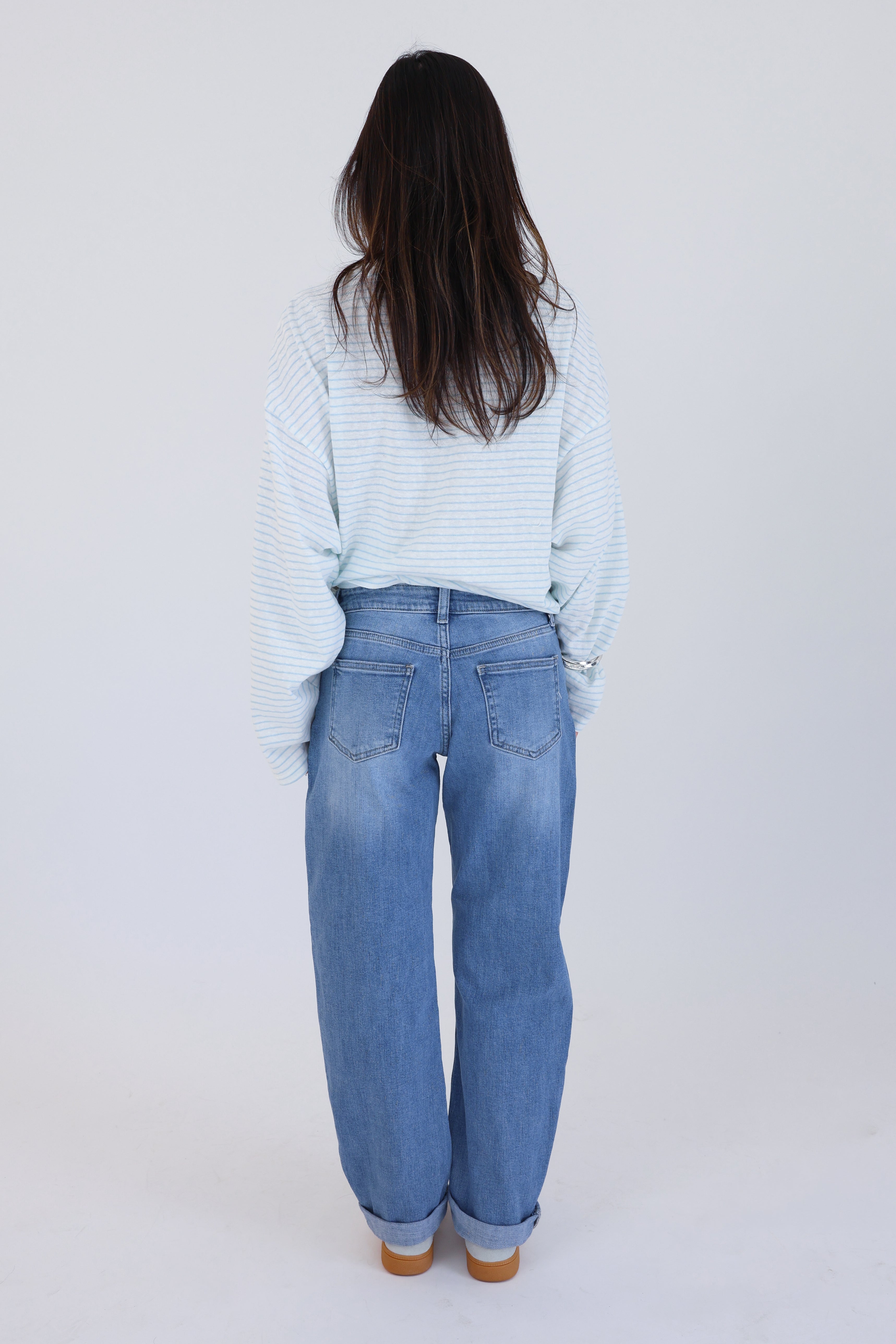 Person wearing a light blue striped shirt and jeans on a white background