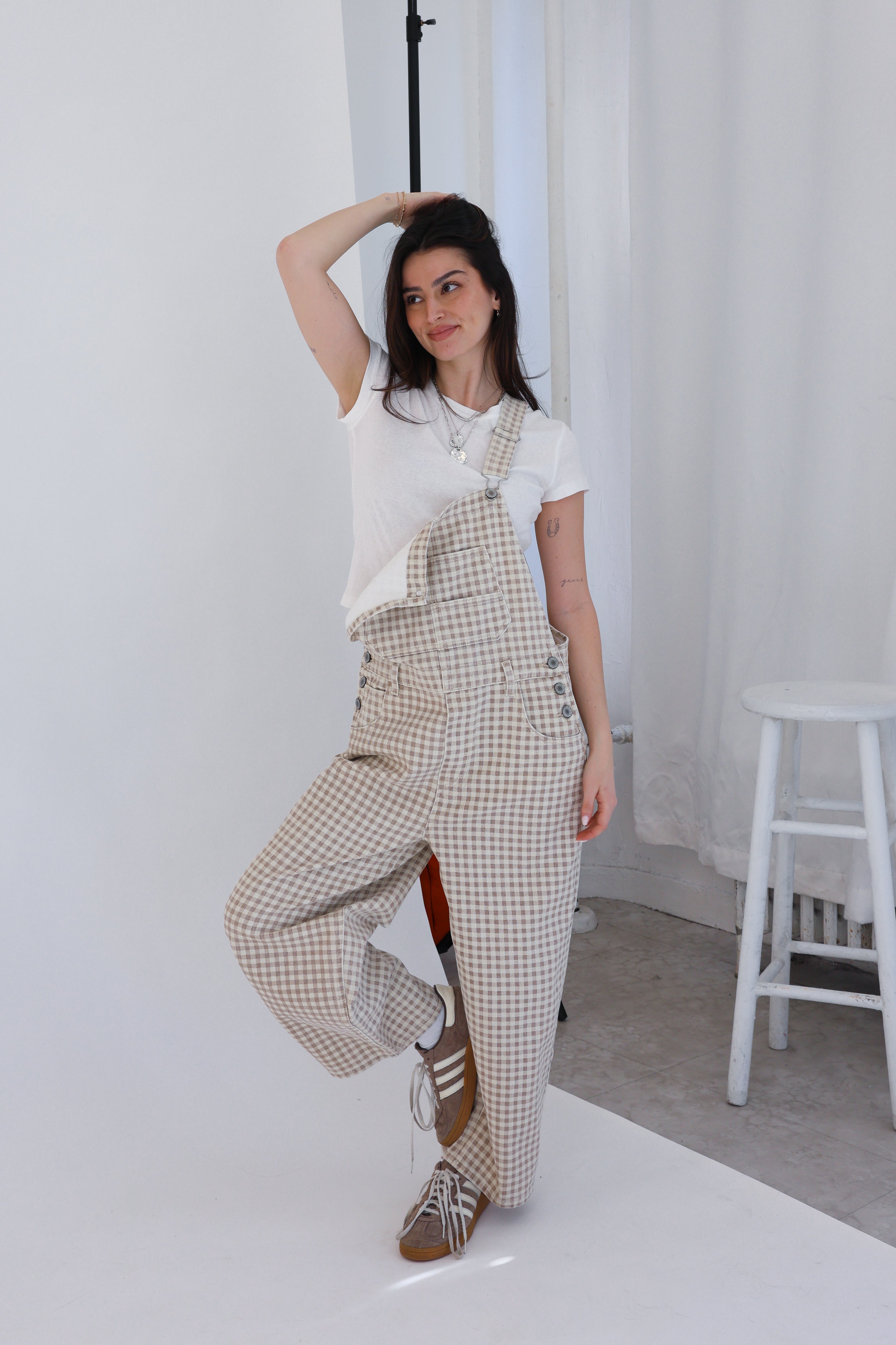 Woman wearing checkered overalls in a minimal indoor setting