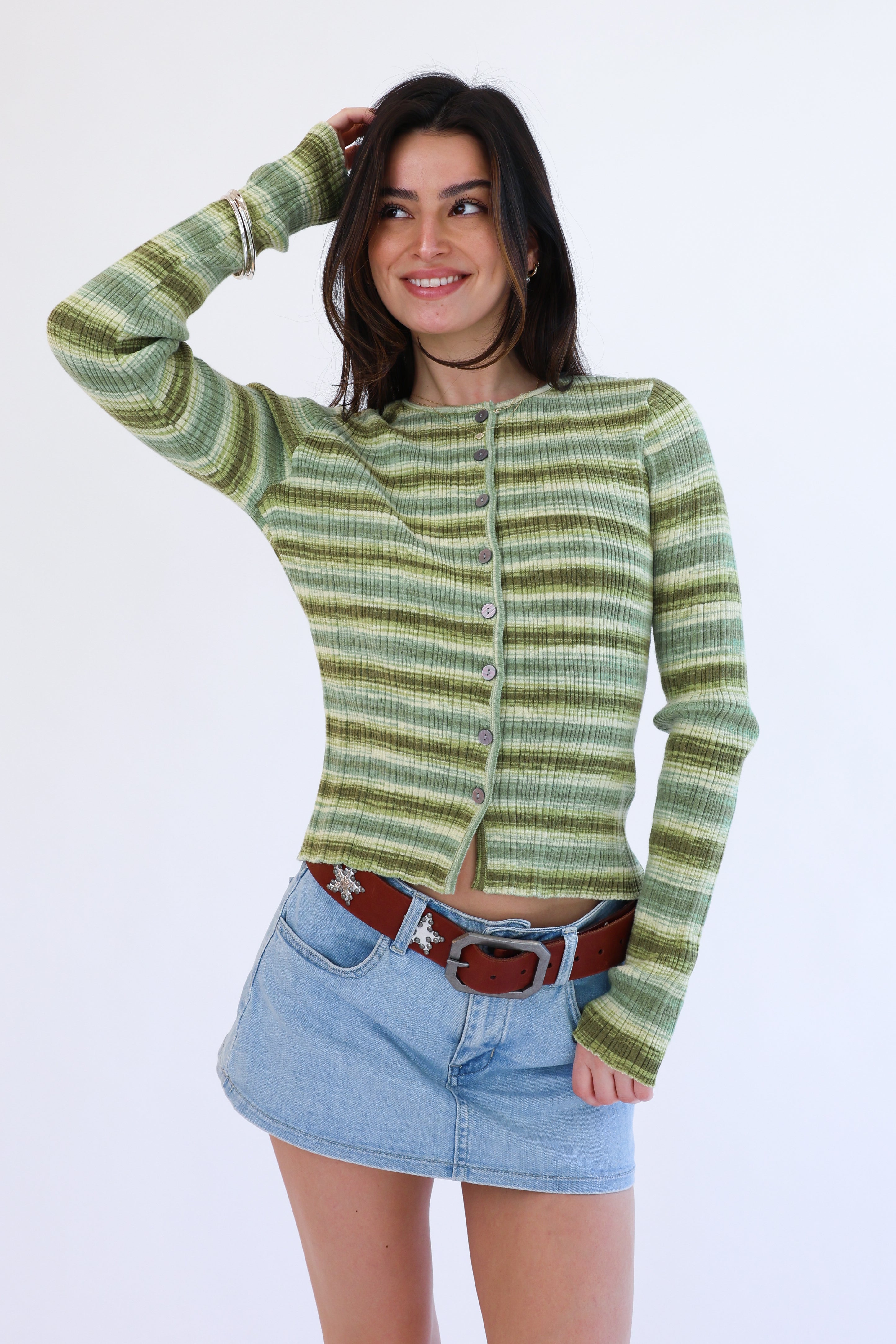 Woman wearing a green striped sweater and denim skirt on a white background